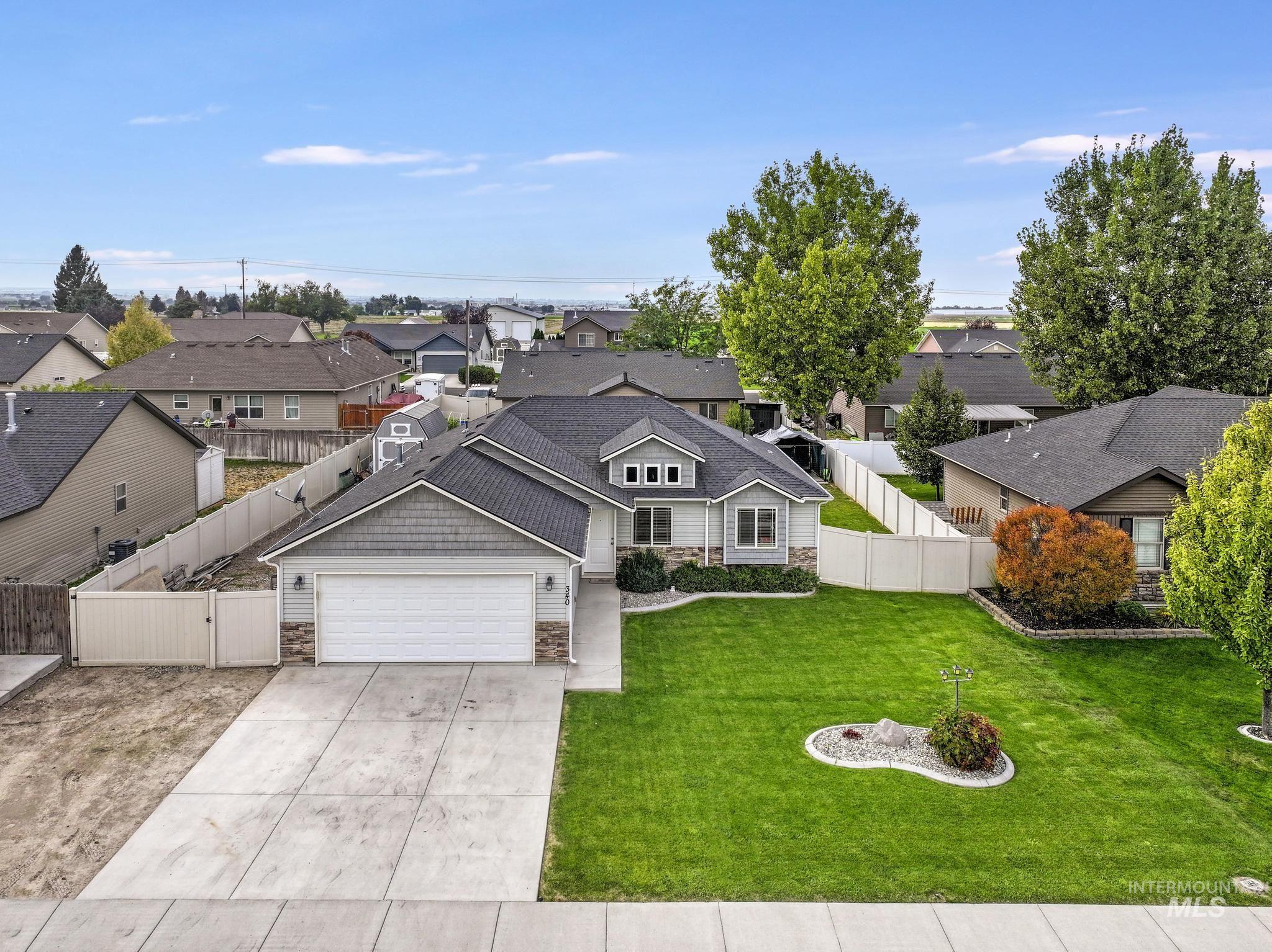 Traditional-style house featuring stone siding, a residential view, an attached garage, and concrete driveway