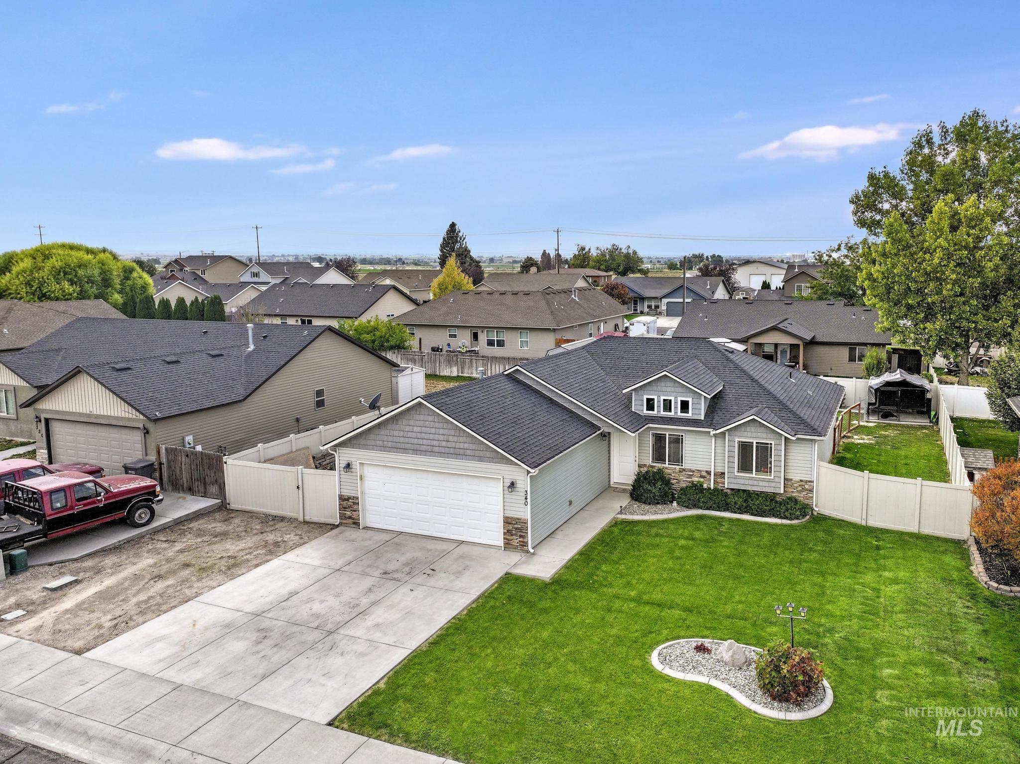 View of front facade featuring stone siding, a residential view, concrete driveway, a garage, and roof with shingles
