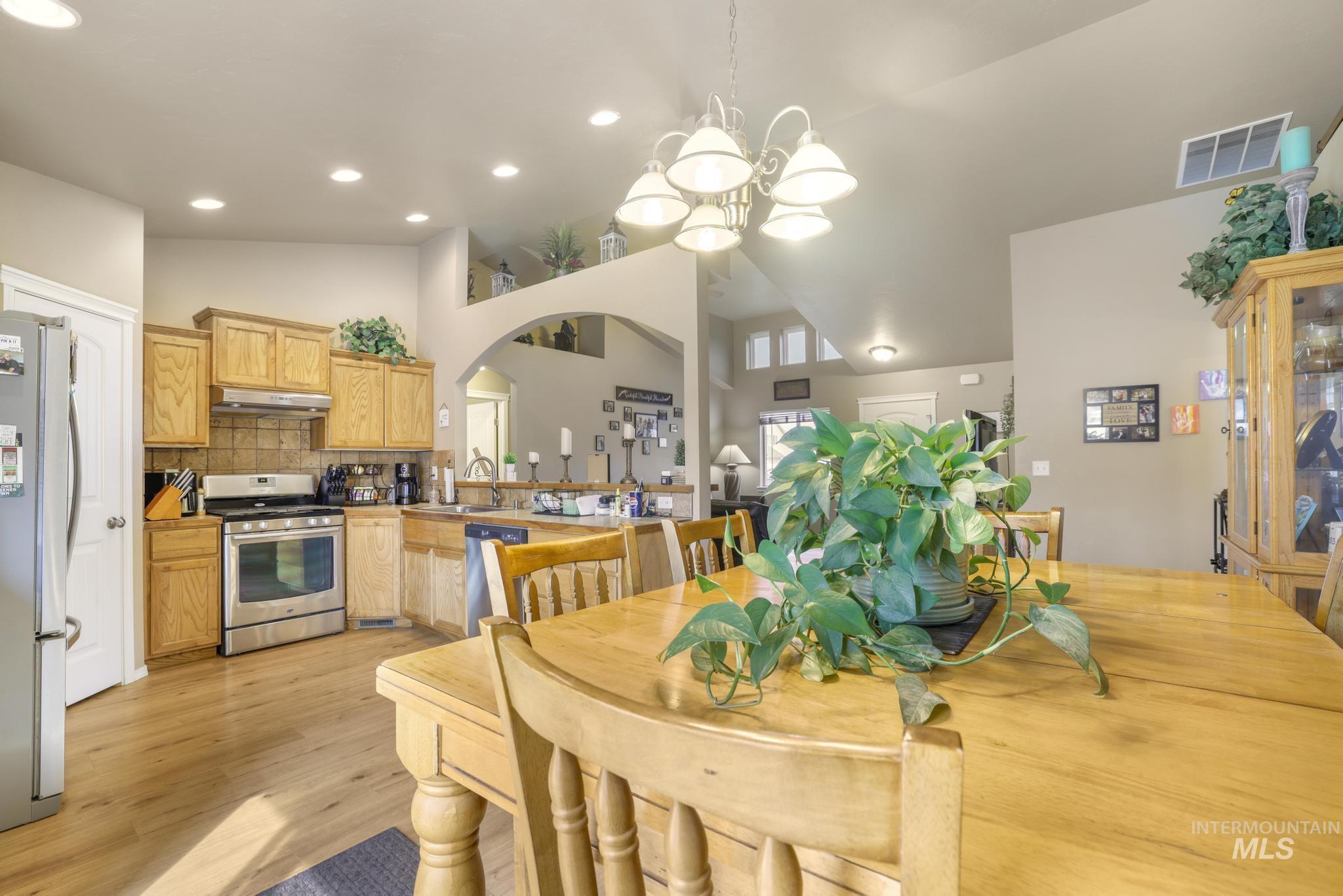 Dining room with arched walkways, recessed lighting, light wood-style flooring, and high vaulted ceiling