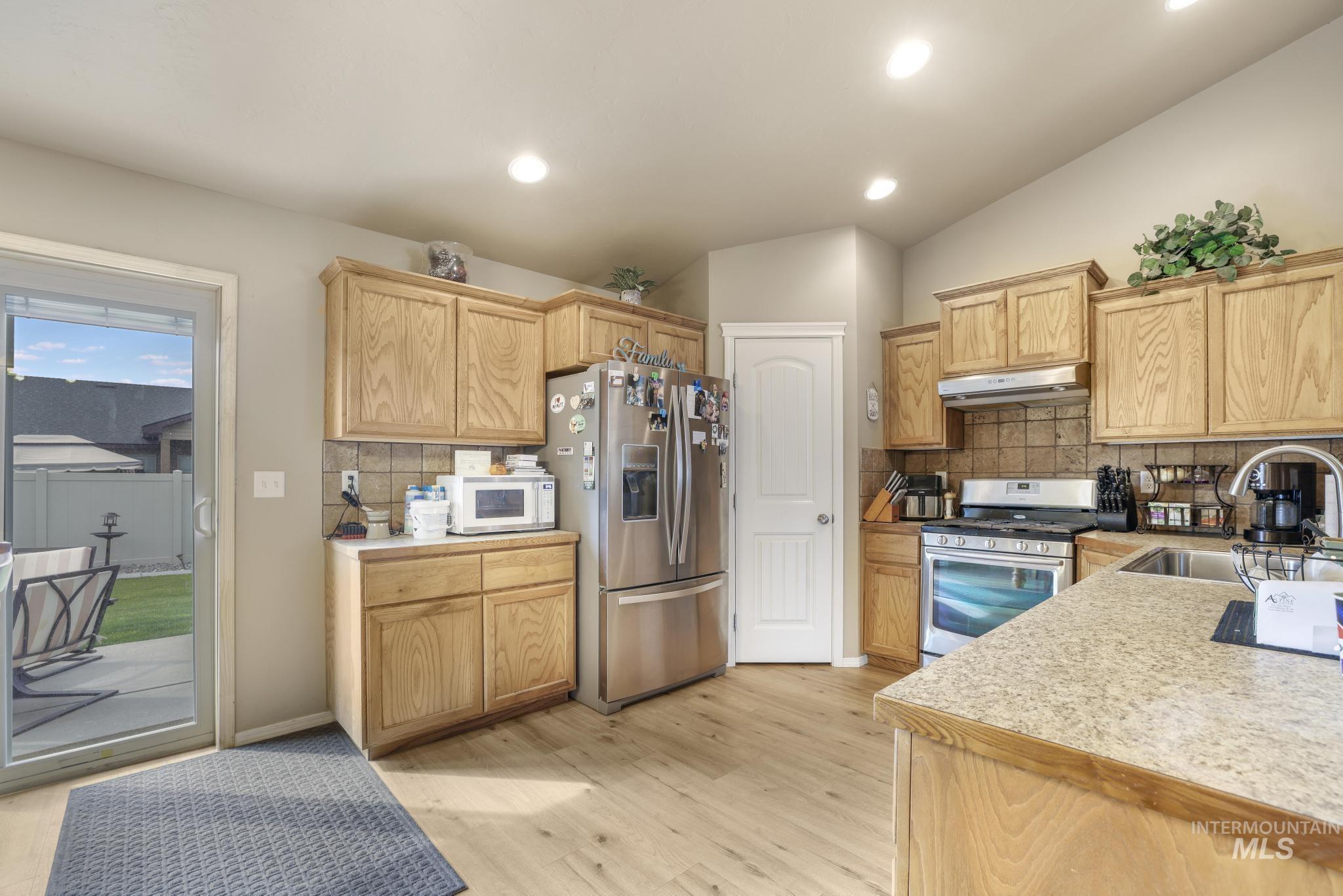 Kitchen with light countertops, stainless steel appliances, tasteful backsplash, light wood finished floors, and recessed lighting