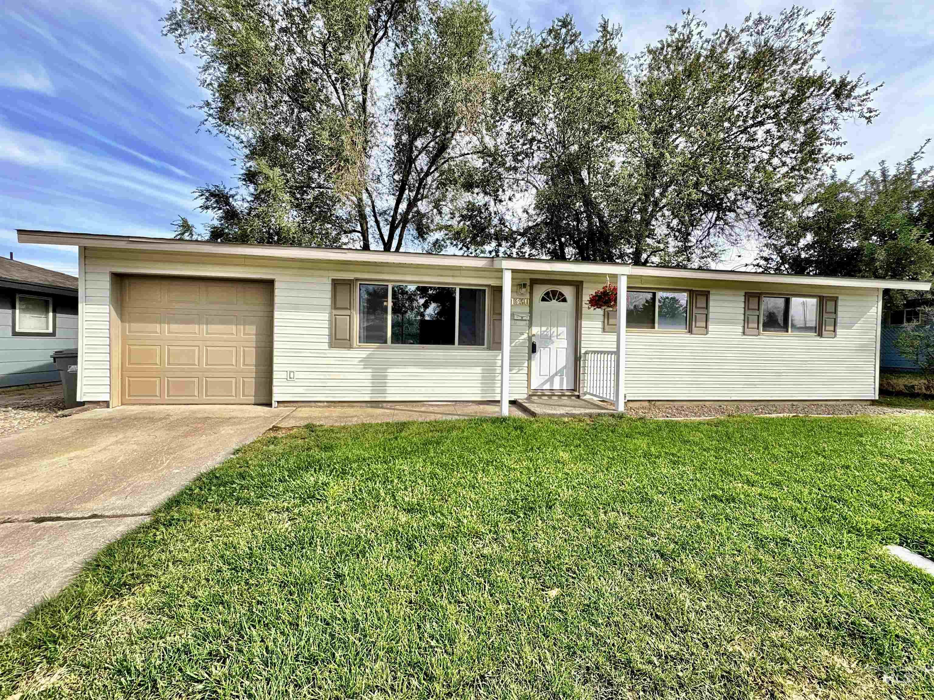 Ranch-style house featuring a front lawn, driveway, and an attached garage