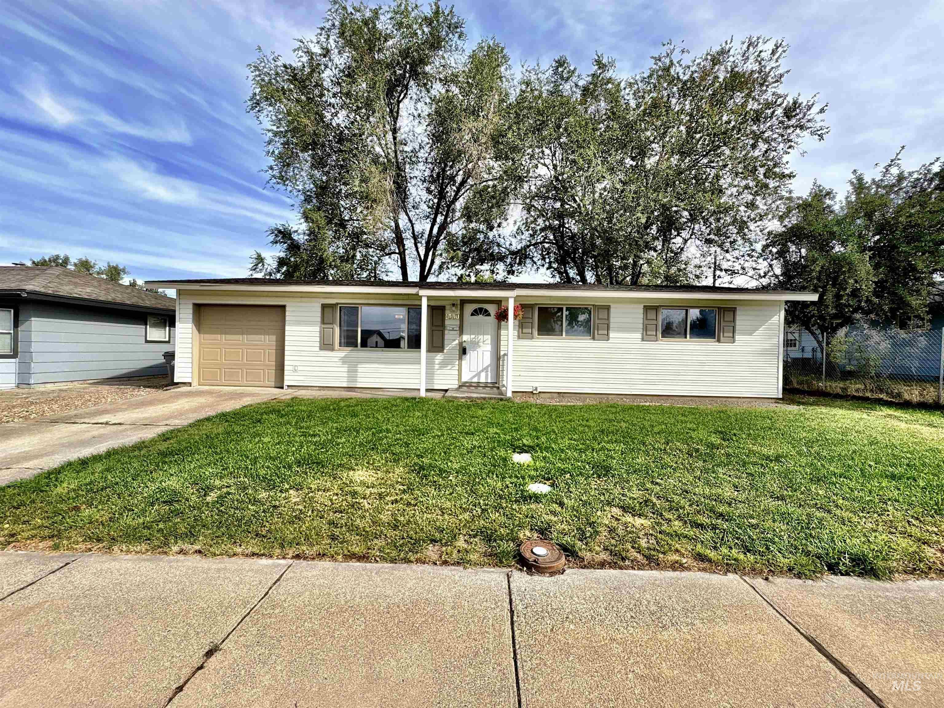 Ranch-style home featuring a front yard, concrete driveway, and a garage