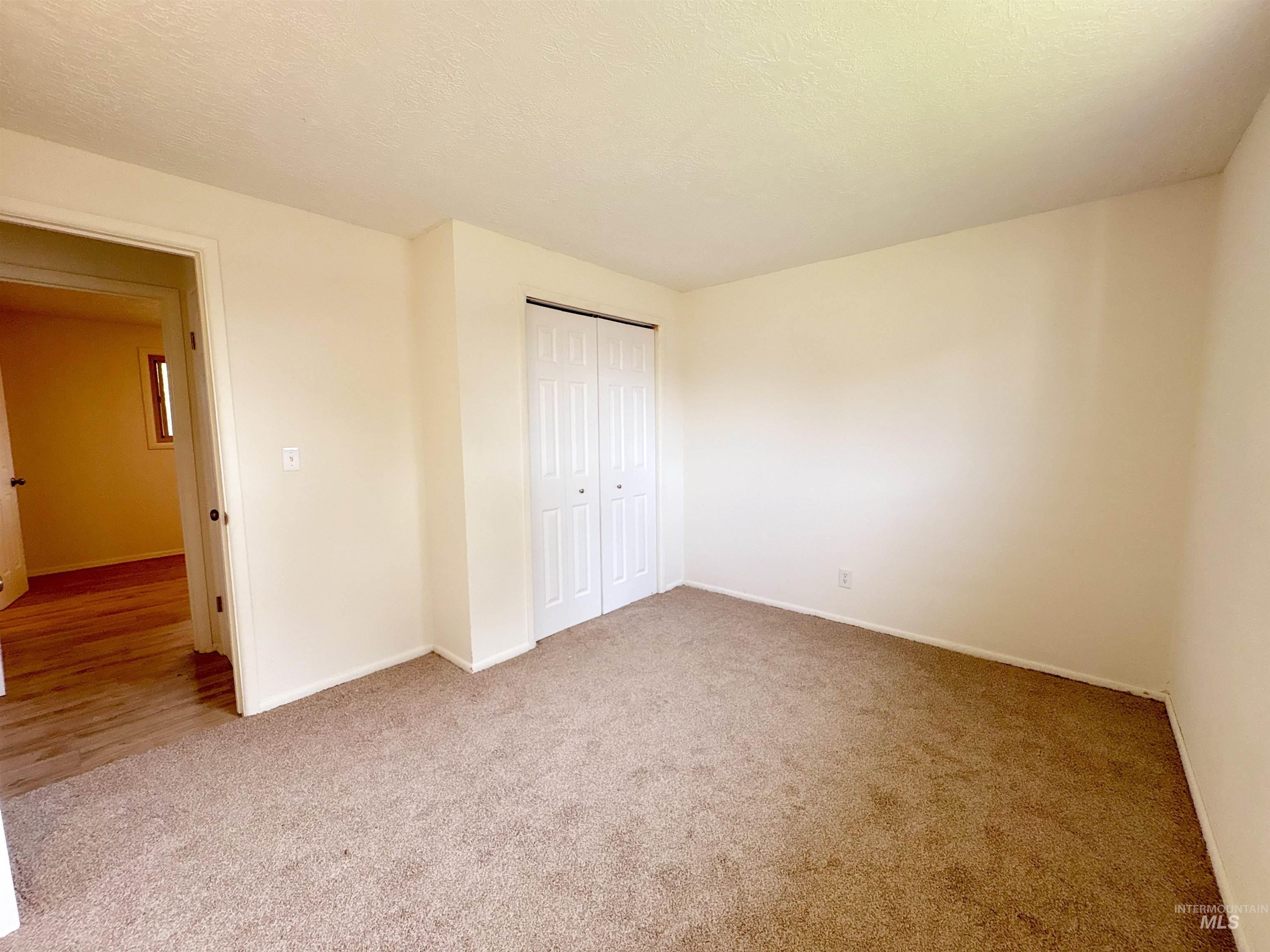 Unfurnished bedroom featuring light carpet, a closet, and a textured ceiling