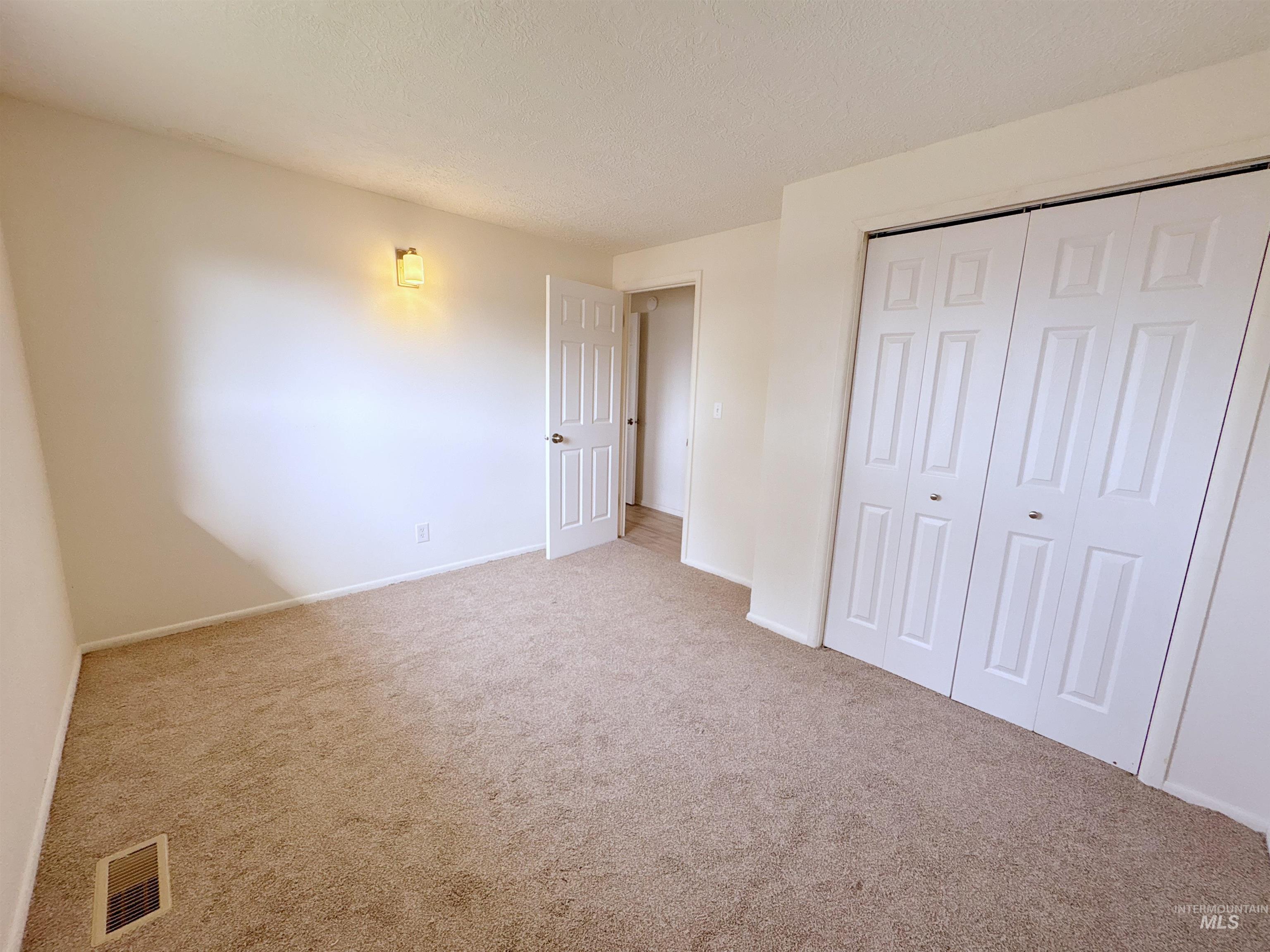 Unfurnished bedroom featuring a closet, carpet floors, and a textured ceiling