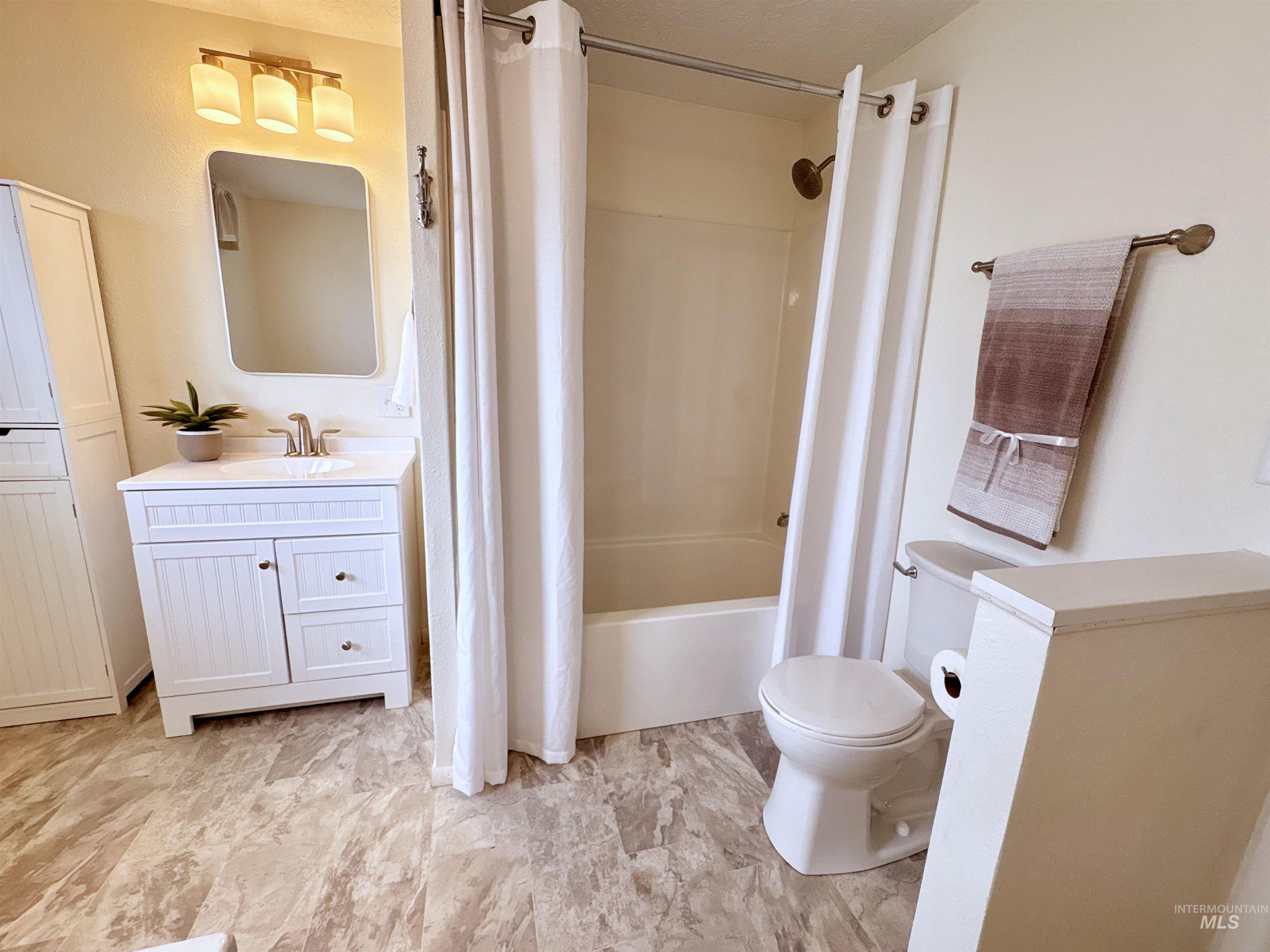 Bathroom with shower / bath combination with curtain and vanity