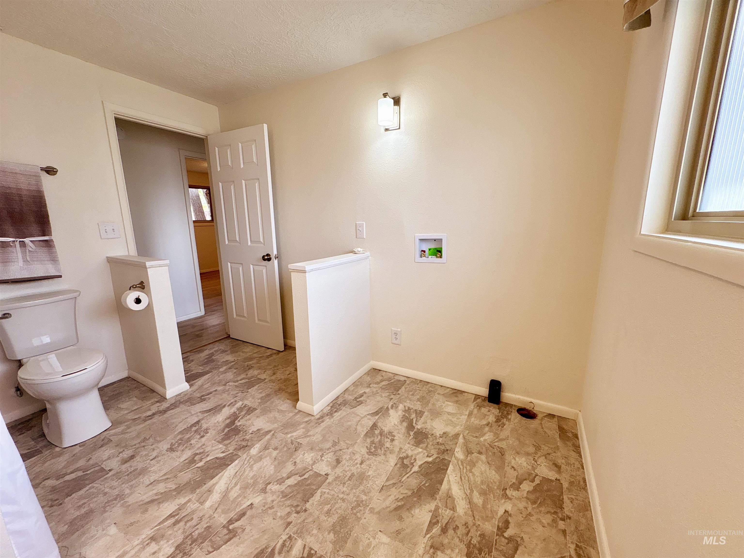 Laundry room featuring healthy amount of natural light, hookup for a washing machine, and a textured ceiling