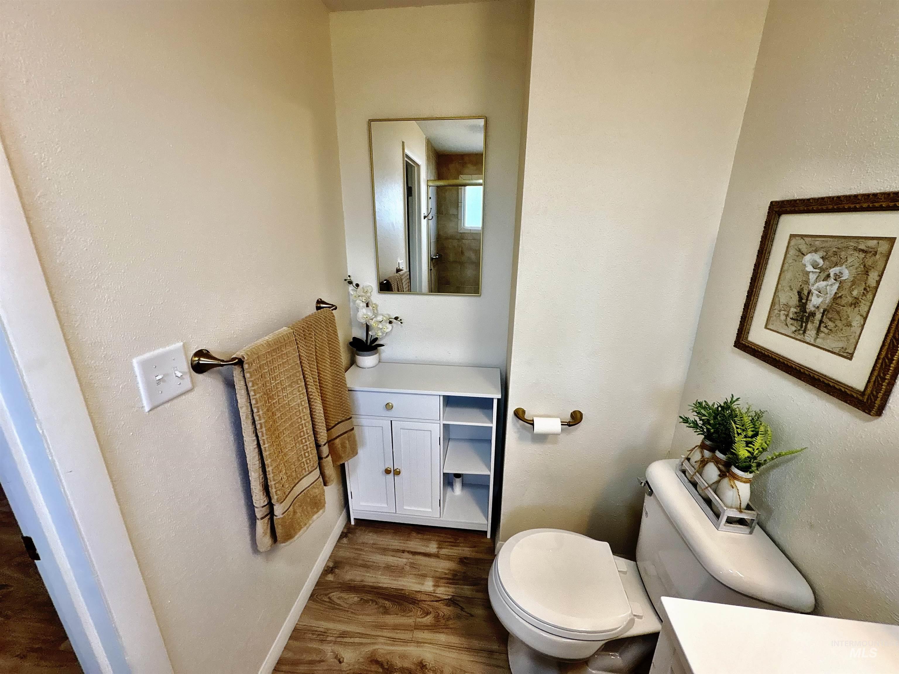 Full bath with dark wood-style flooring, vanity, a textured wall, and a shower with door