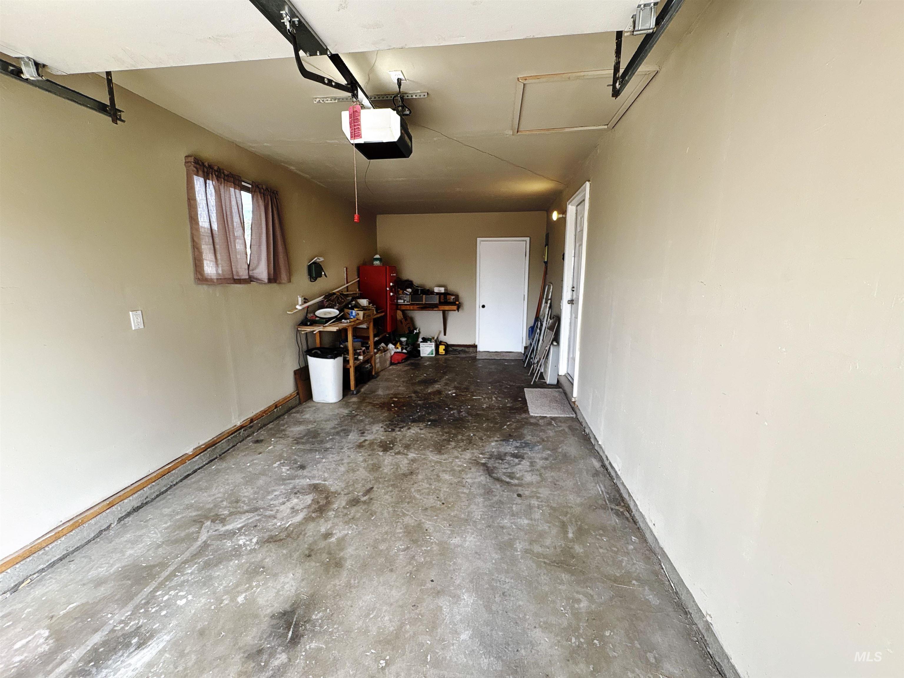 Garage featuring a garage door opener and baseboards