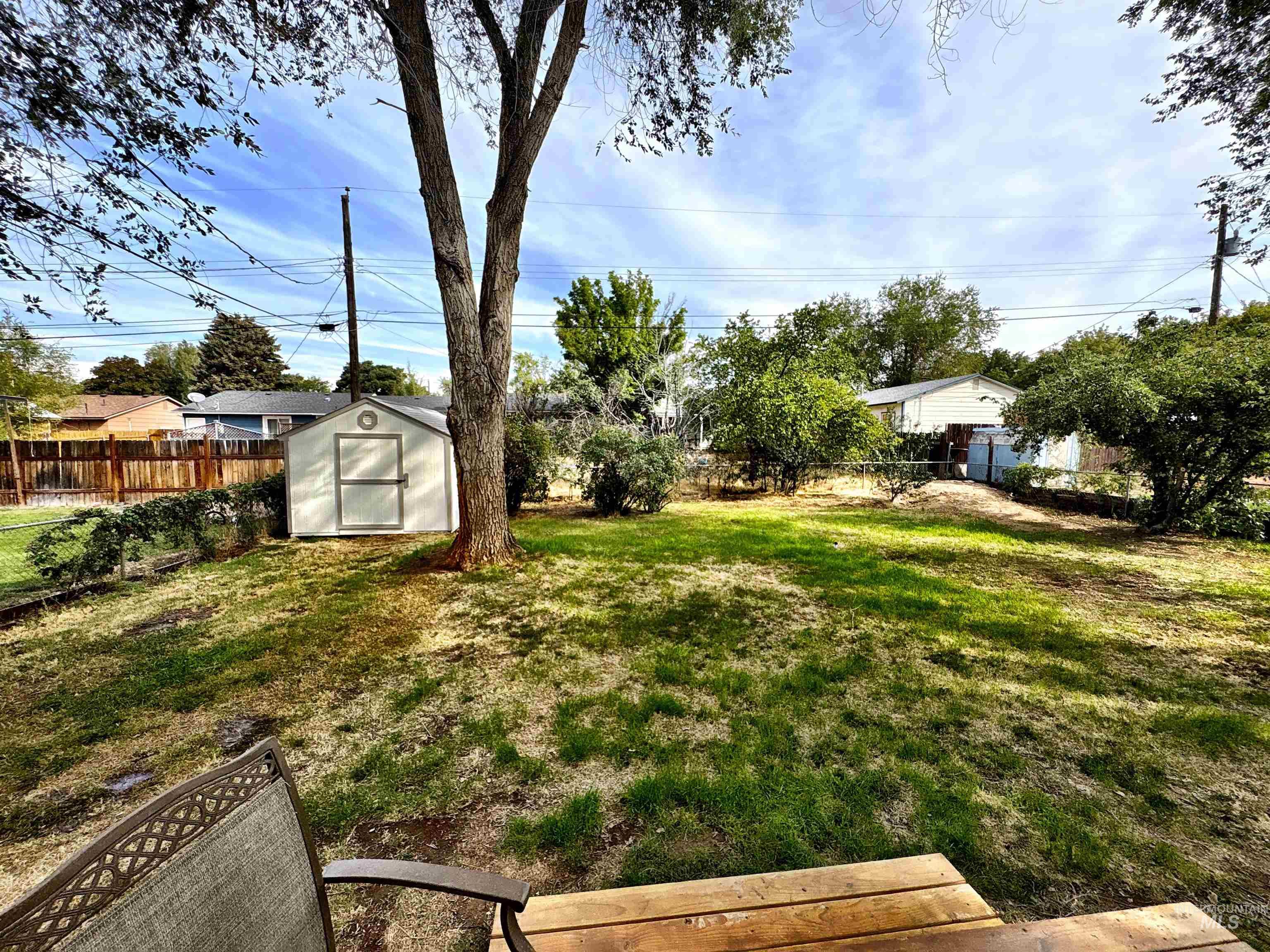 Fenced backyard featuring a storage unit