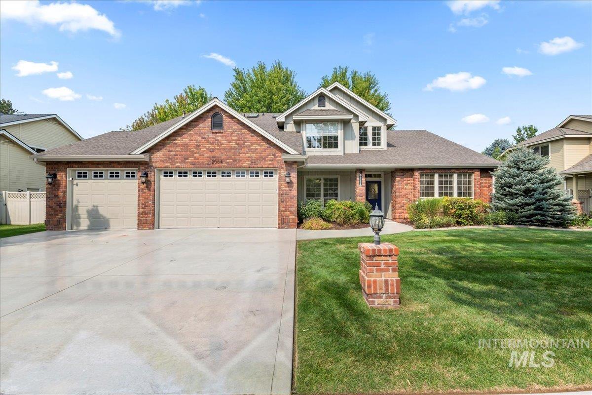View of front facade featuring roof with shingles, brick siding, a garage, driveway, and a front yard