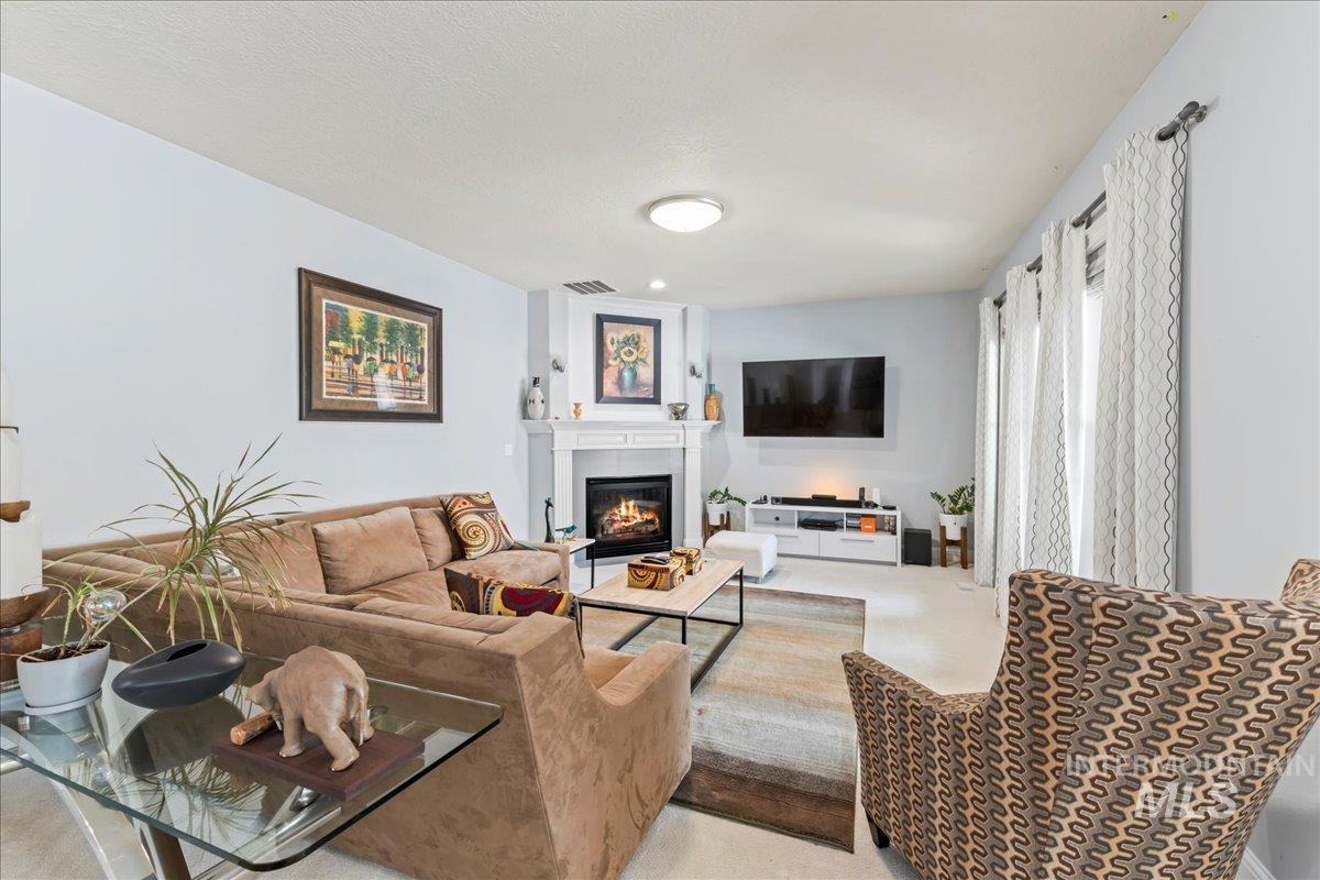 Living area featuring a glass covered fireplace and carpet flooring