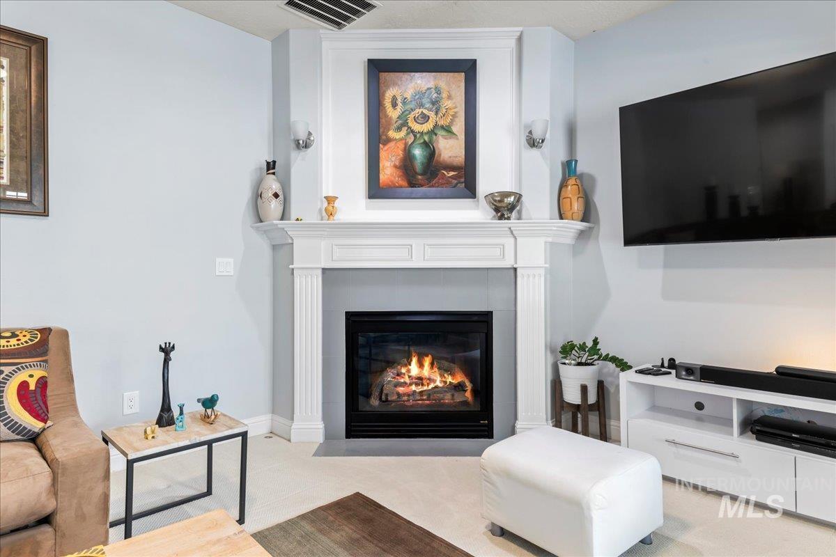 Living area with a fireplace with flush hearth and carpet flooring