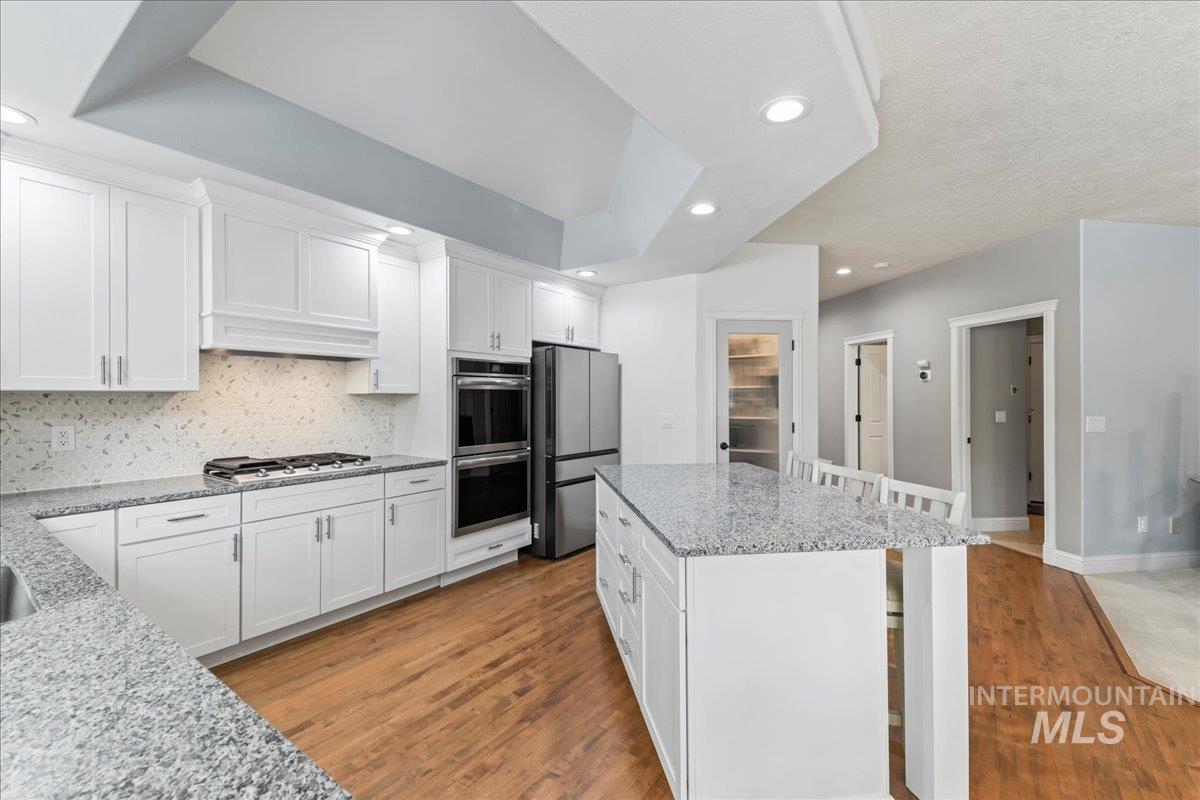 Kitchen featuring a kitchen breakfast bar, white cabinets, light wood-style floors, and recessed lighting