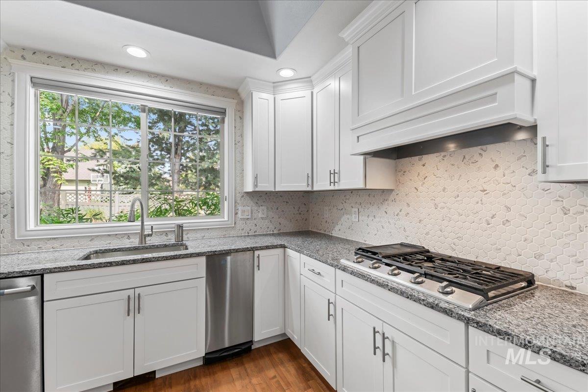 Kitchen featuring light stone counters, white cabinets, recessed lighting, dark wood finished floors, and stainless steel appliances