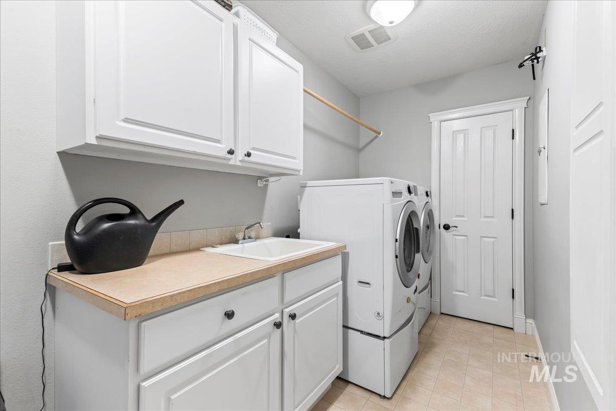 Laundry room featuring cabinet space, washer and clothes dryer, and light tile patterned flooring
