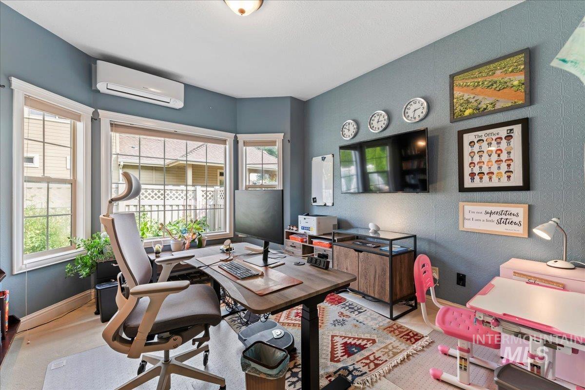 Home office featuring a wall mounted air conditioner and a textured wall