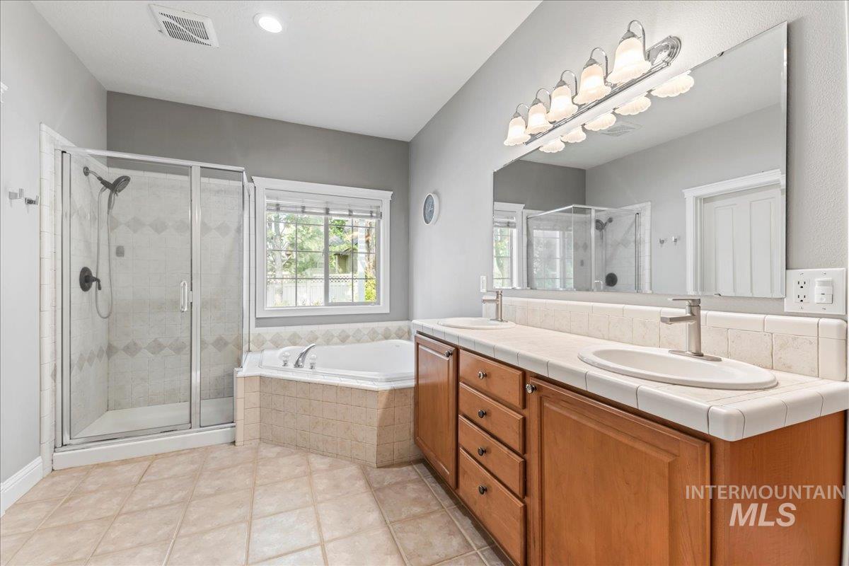 Bathroom featuring a shower stall, double vanity, a garden tub, recessed lighting, and light tile patterned floors