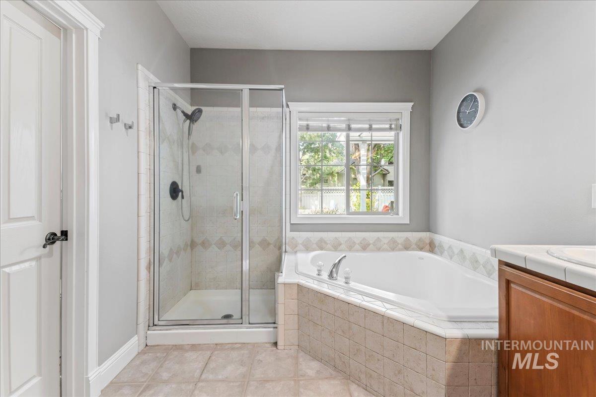 Full bathroom featuring a shower stall, a garden tub, vanity, and light tile patterned floors
