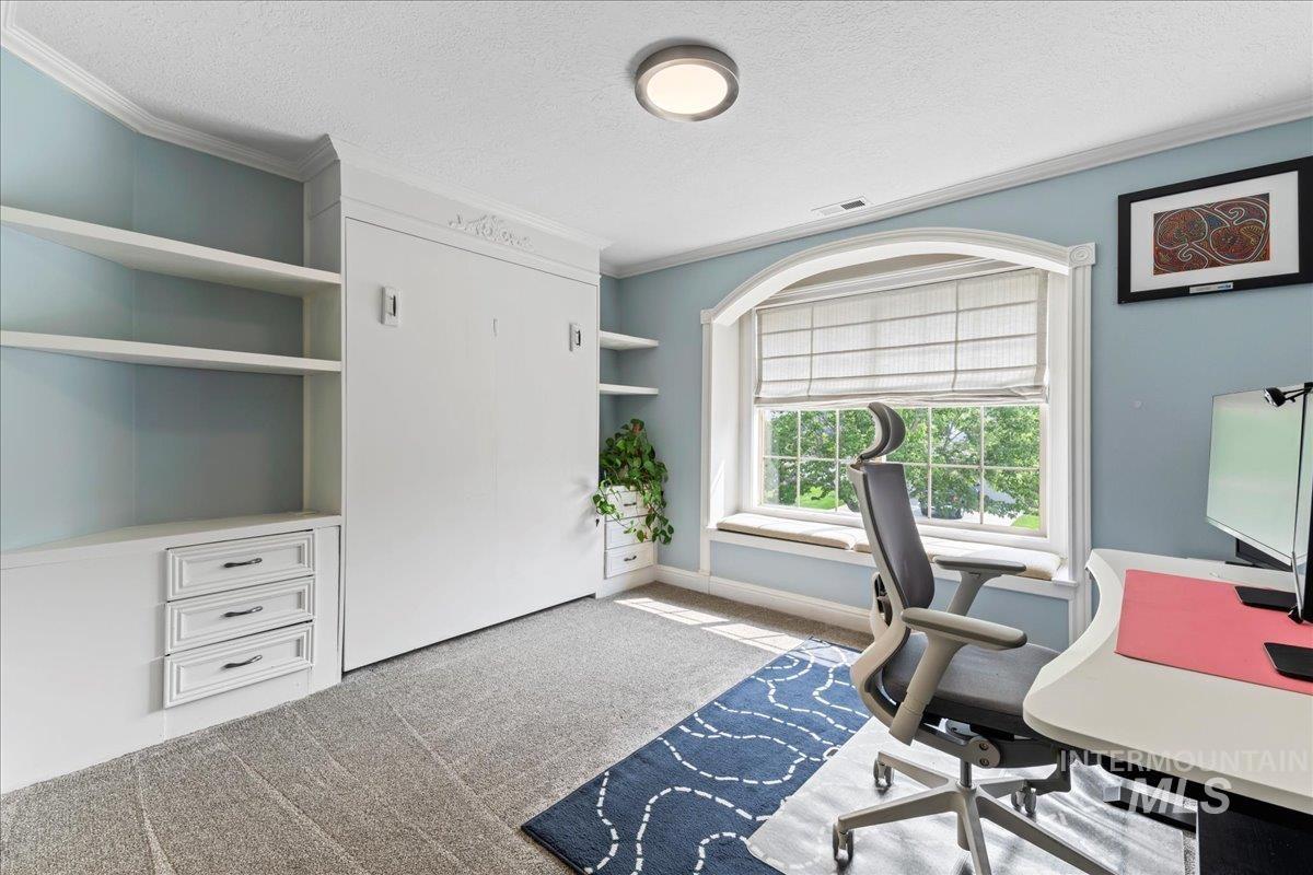 Carpeted office space with a textured ceiling, ornamental molding, and built in shelves
