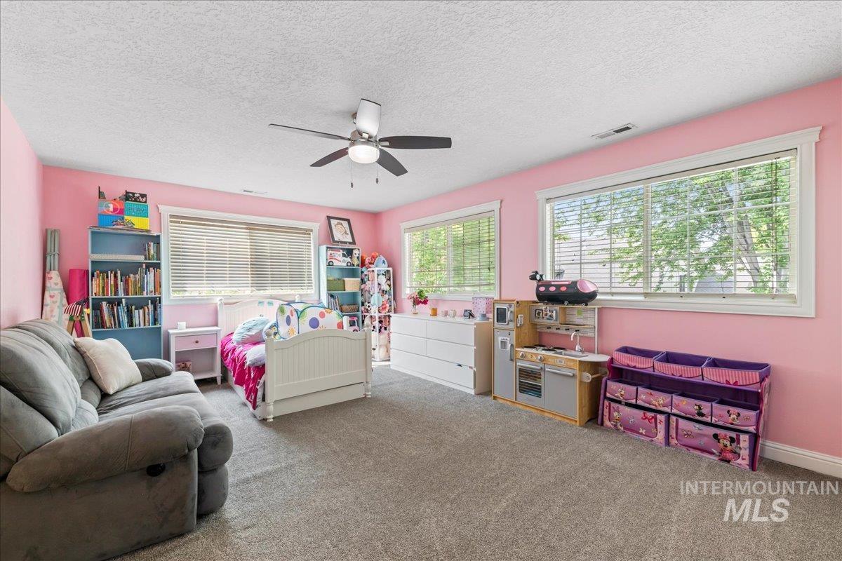 Carpeted bedroom featuring a textured ceiling and ceiling fan