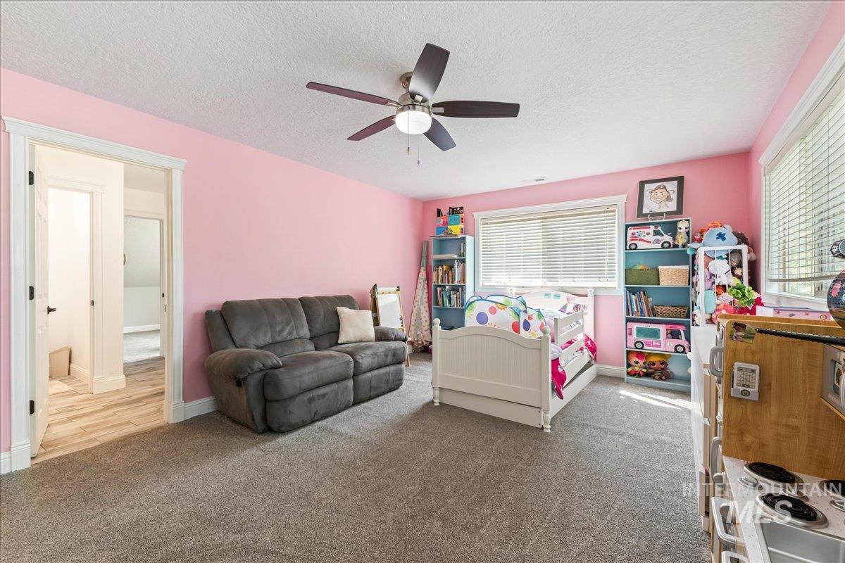 Bedroom featuring carpet floors, a textured ceiling, and a ceiling fan