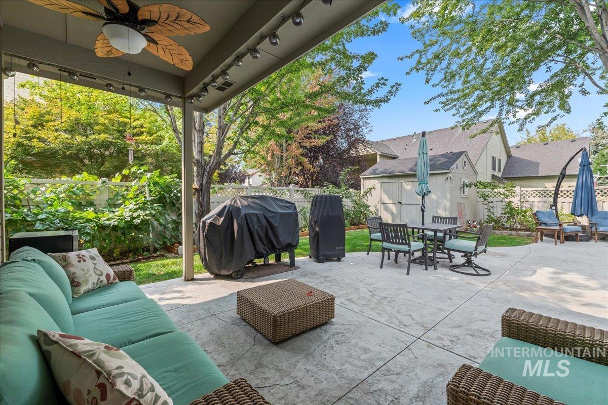 Fenced backyard with an outdoor hangout area, area for grilling, a patio, and a ceiling fan
