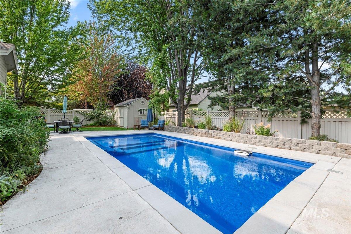 View of swimming pool featuring a shed, a fenced backyard, and a patio