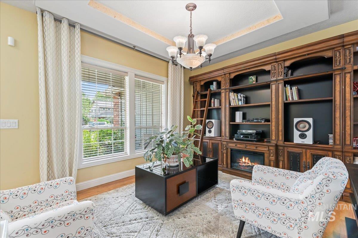 Sitting room with light wood-style flooring, a tray ceiling, and a chandelier