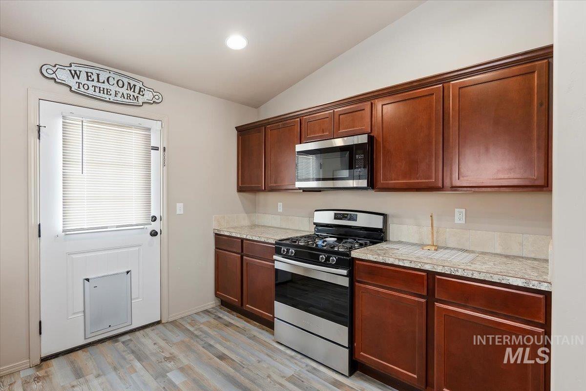 Kitchen with appliances with stainless steel finishes, light countertops, vaulted ceiling, light wood-style floors, and recessed lighting