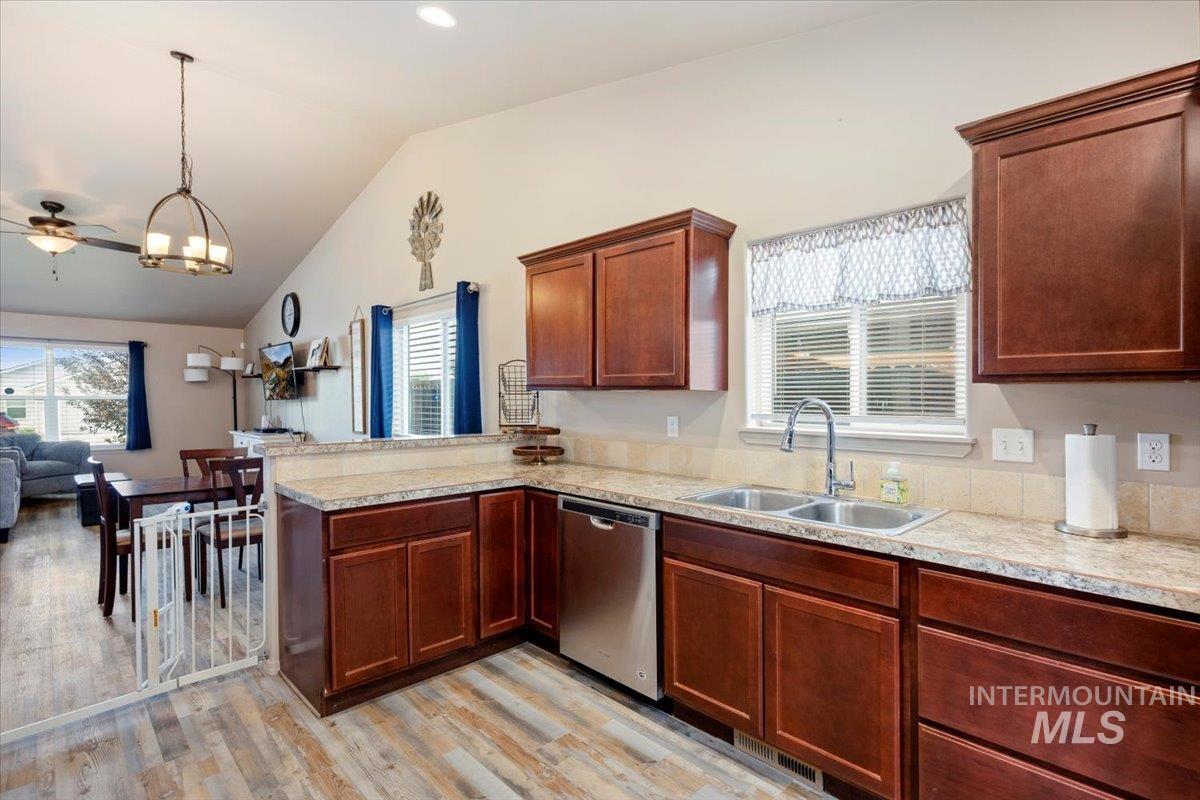 Kitchen featuring vaulted ceiling, a peninsula, healthy amount of natural light, open floor plan, and light wood-style floors