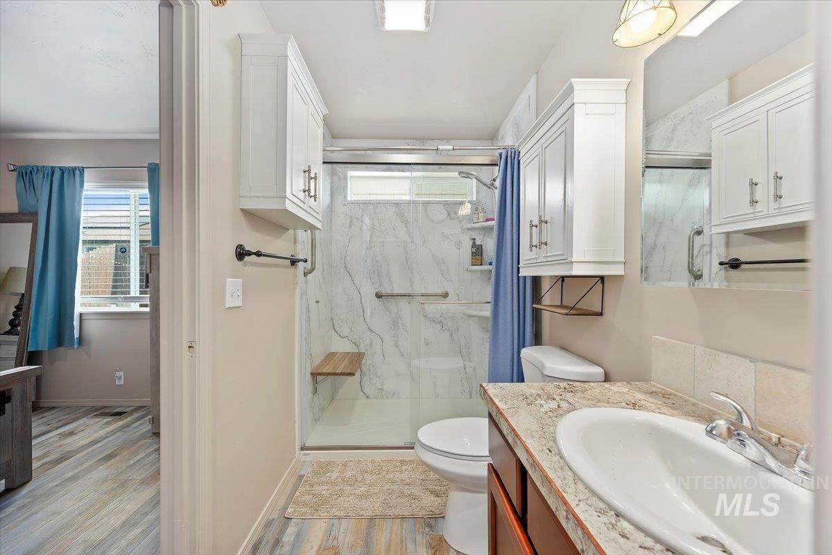 Bathroom featuring a marble finish shower, vanity, and light wood-type flooring