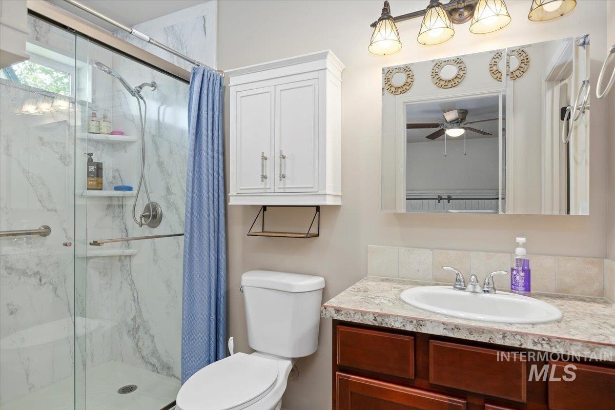 Bathroom featuring a marble finish shower, vanity, and a ceiling fan