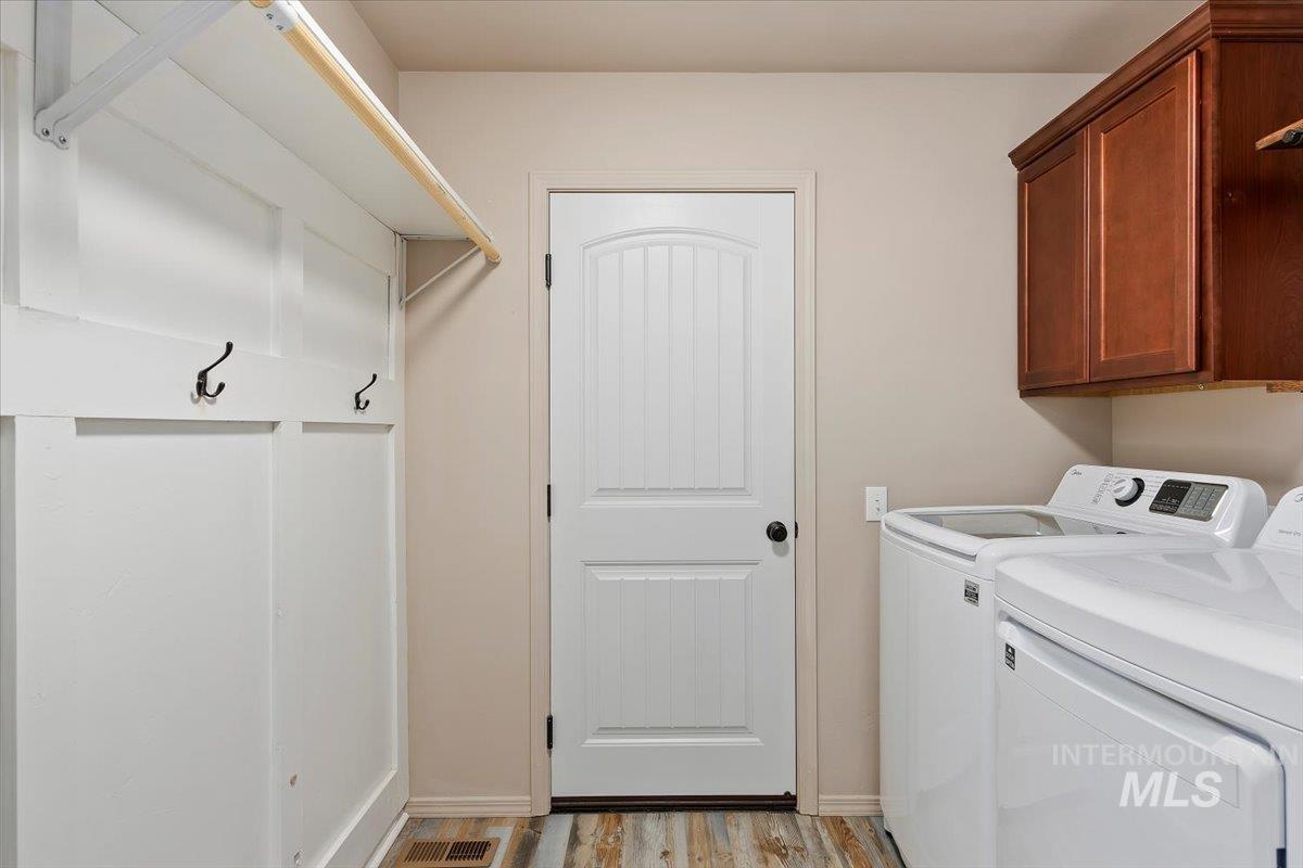 Laundry area featuring washer and clothes dryer, light wood-type flooring, and cabinet space