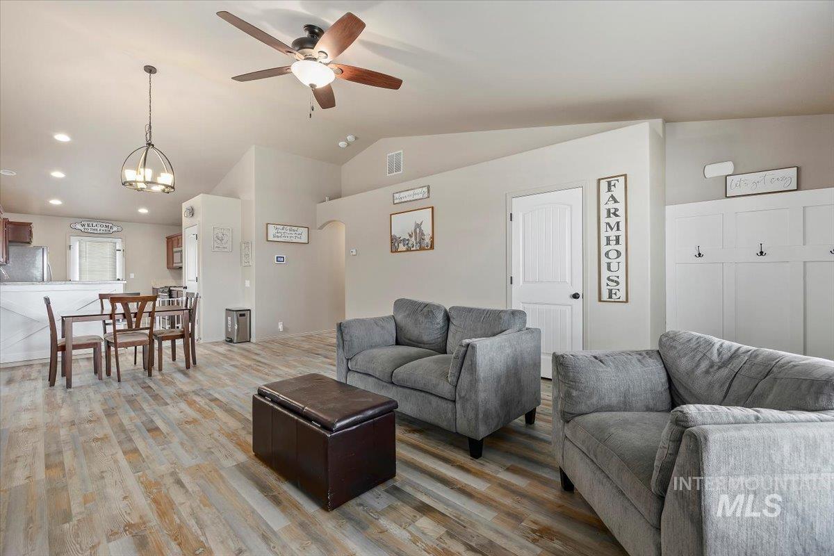 Living area with lofted ceiling, light wood-style flooring, recessed lighting, a ceiling fan, and a chandelier