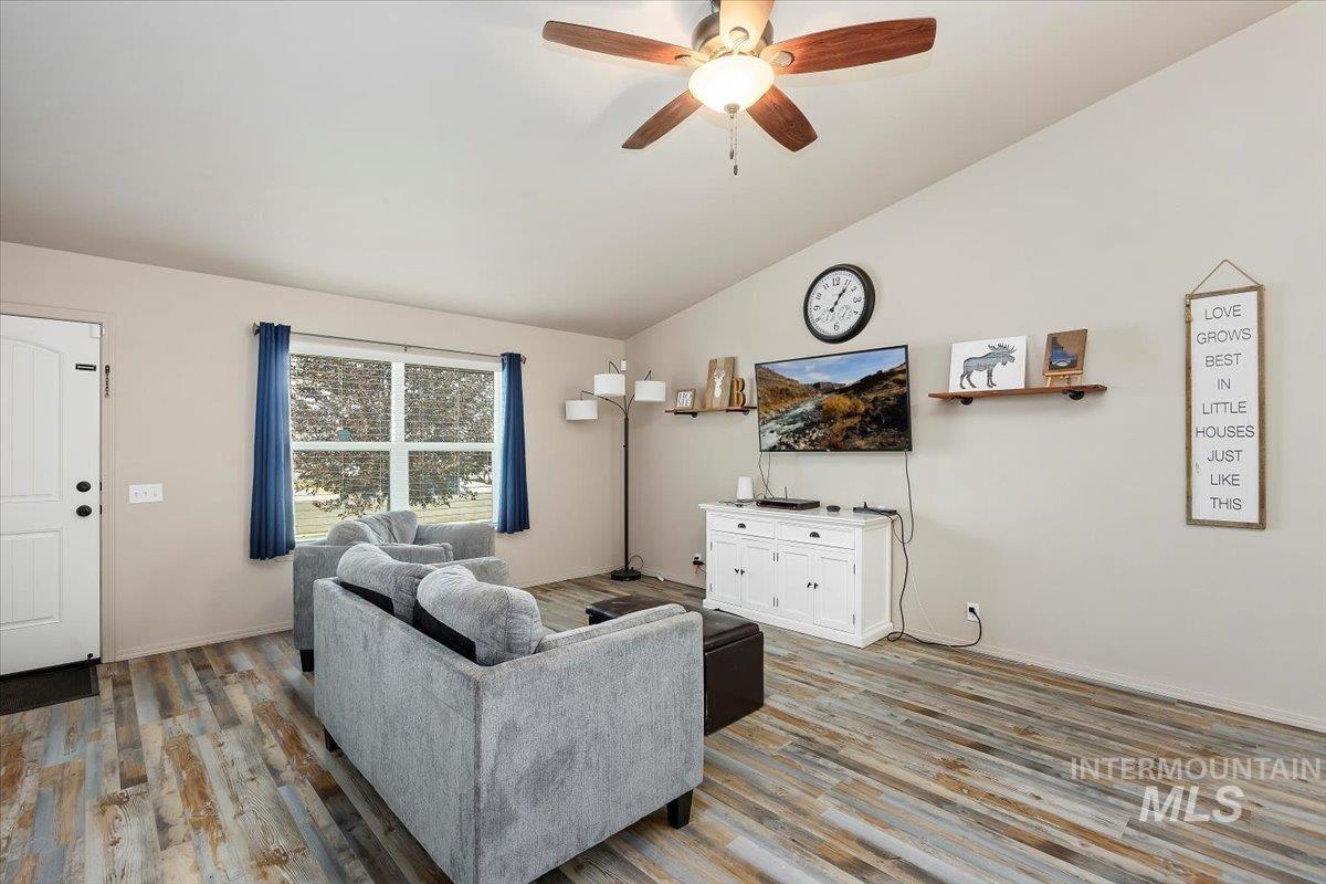 Living room with vaulted ceiling, ceiling fan, and light wood-style flooring
