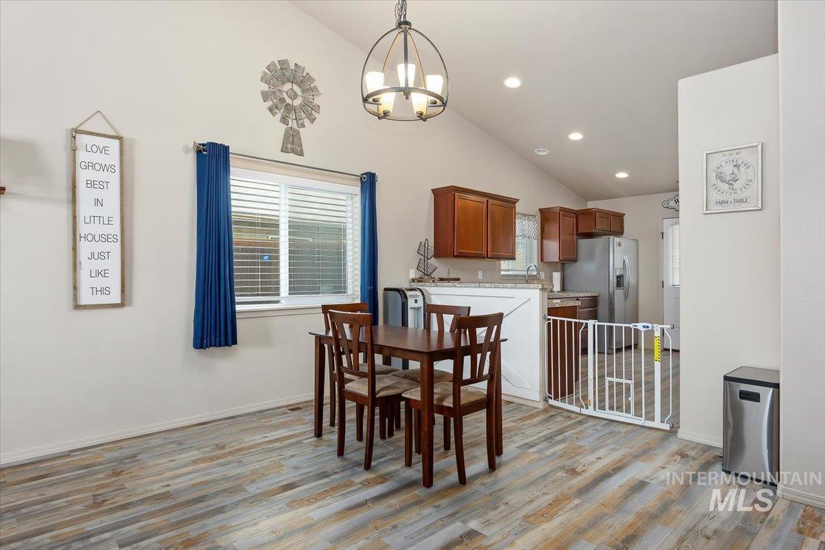 Dining area with light wood finished floors, recessed lighting, high vaulted ceiling, and a chandelier