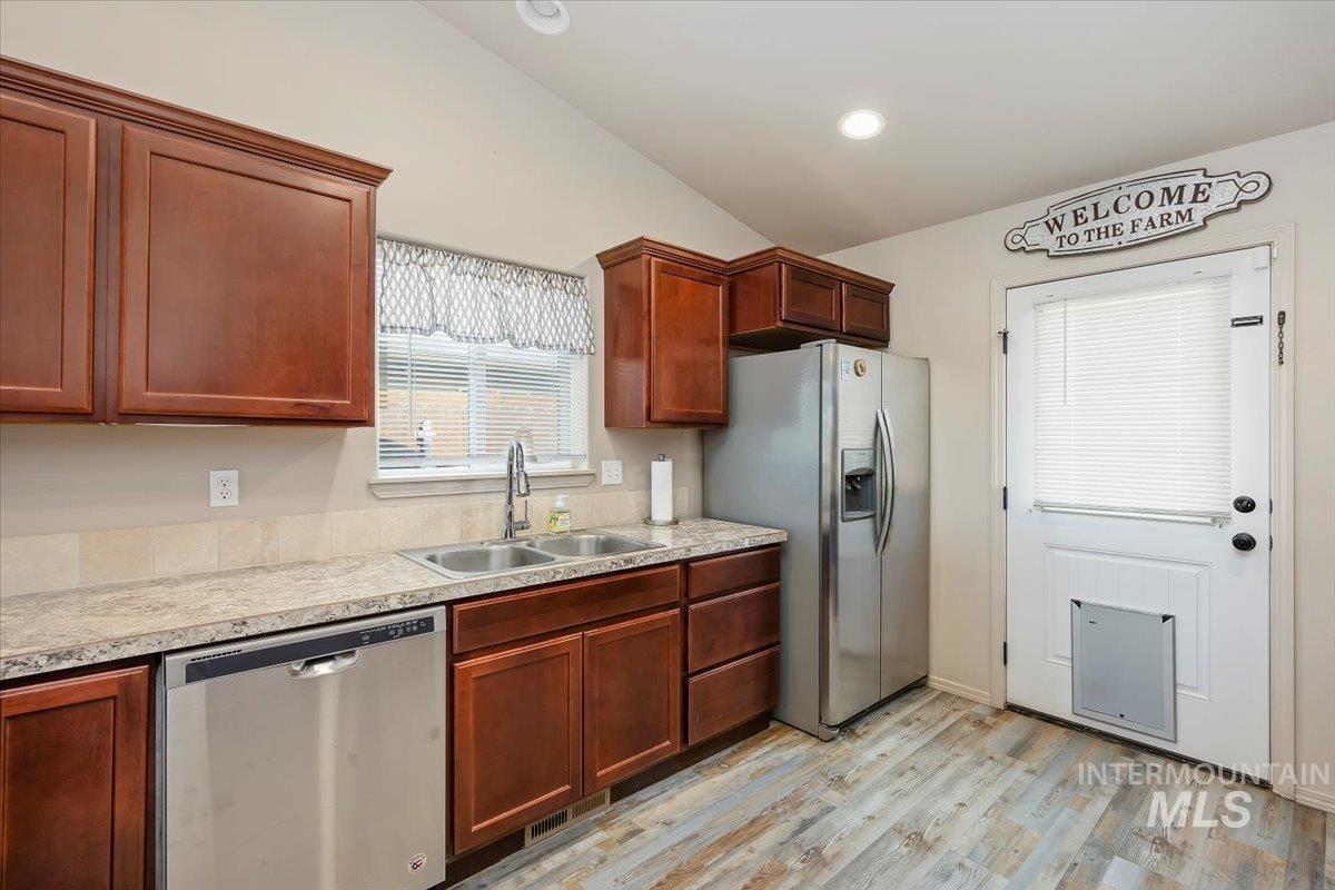 Kitchen with stainless steel appliances, light countertops, light wood finished floors, recessed lighting, and vaulted ceiling