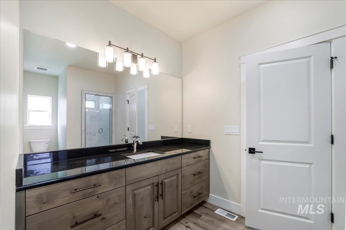 Bathroom featuring vanity, a shower stall, and light wood-style floors