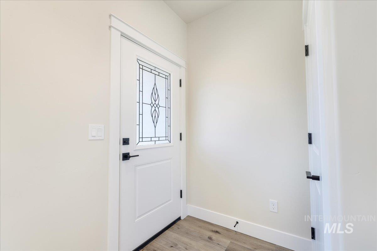 Doorway with baseboards and wood finished floors