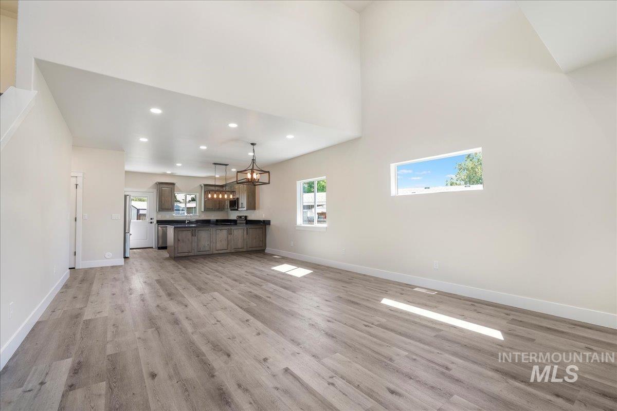Unfurnished living room featuring recessed lighting, a high ceiling, and light wood-style flooring
