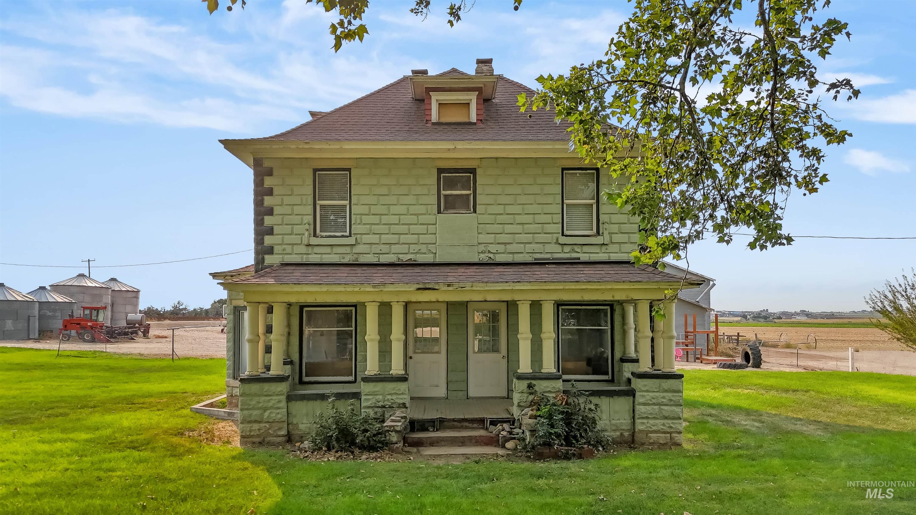 American foursquare style home with a shingled roof, a porch, and a chimney