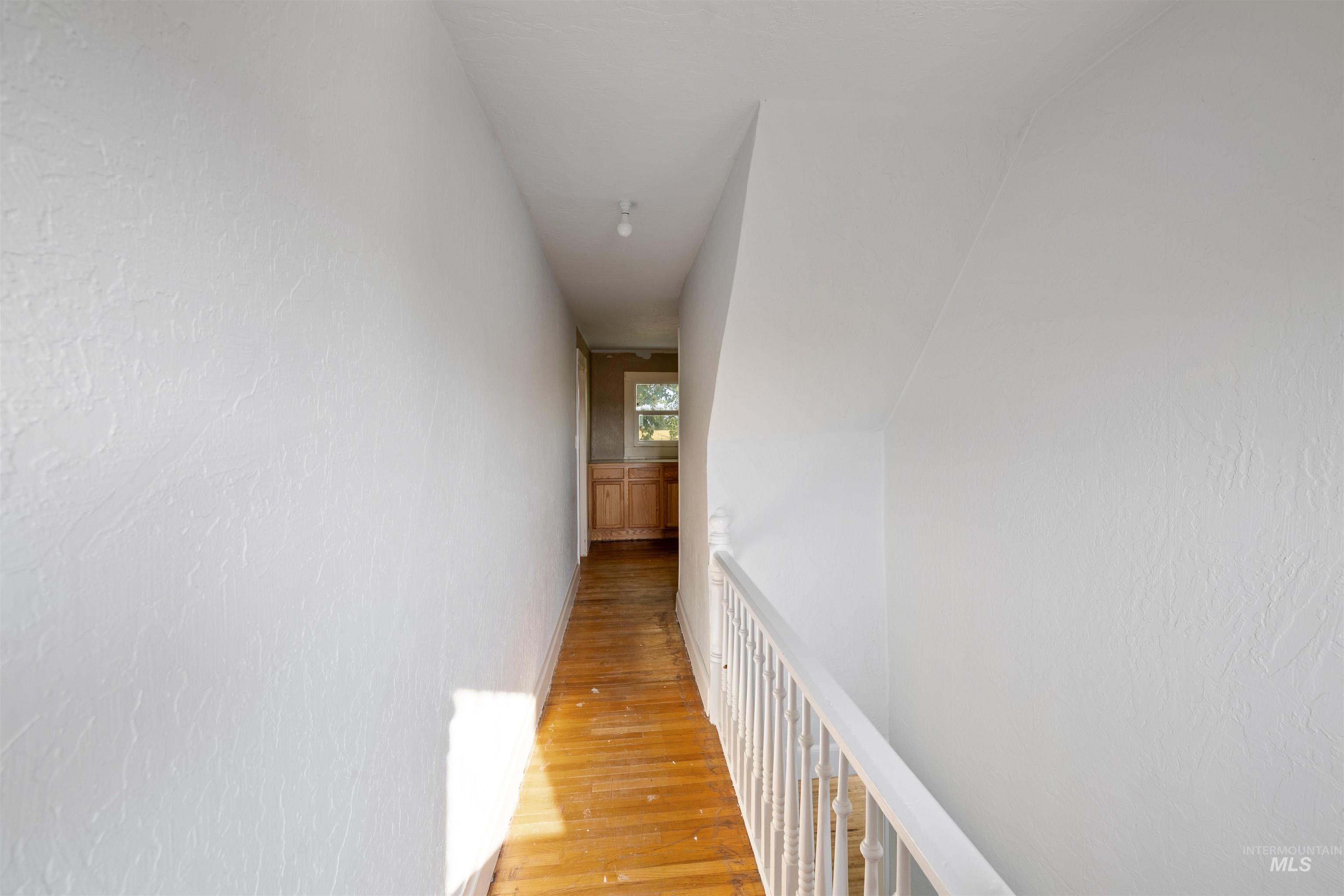 Corridor featuring light wood-style flooring and a textured wall