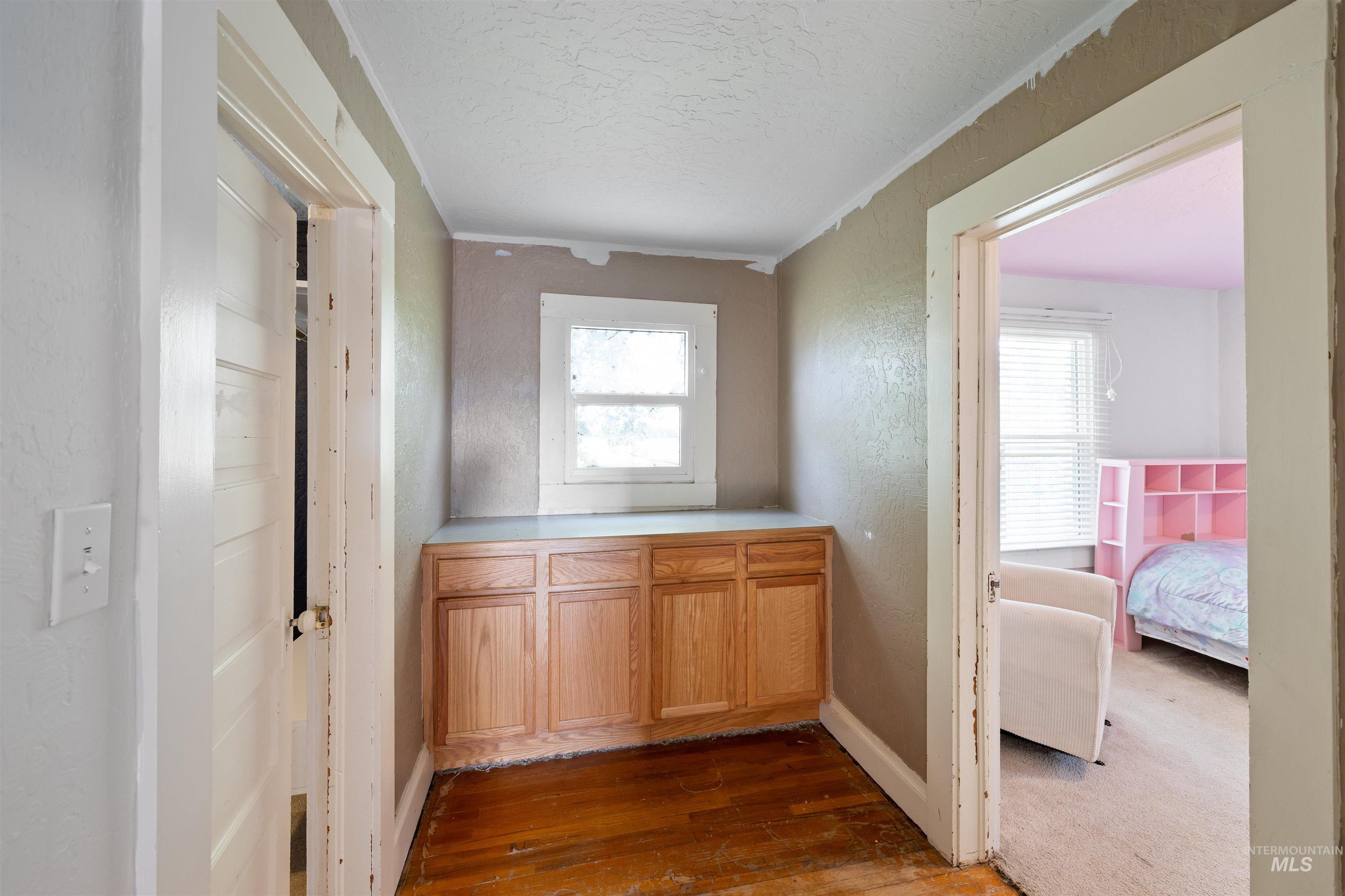 Hallway with healthy amount of natural light, dark wood-style flooring, ornamental molding, a textured wall, and a textured ceiling