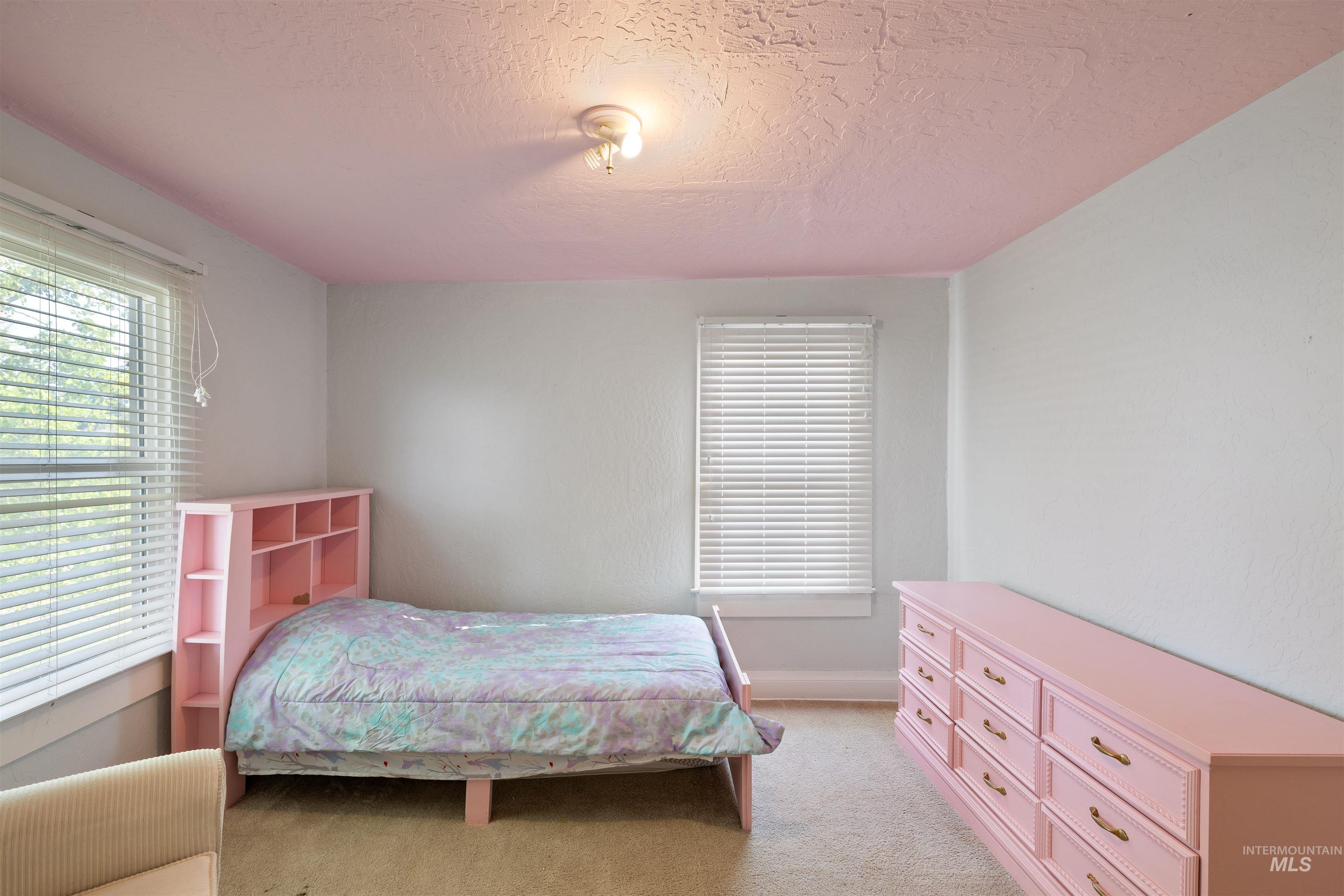 Bedroom featuring light carpet and a textured ceiling