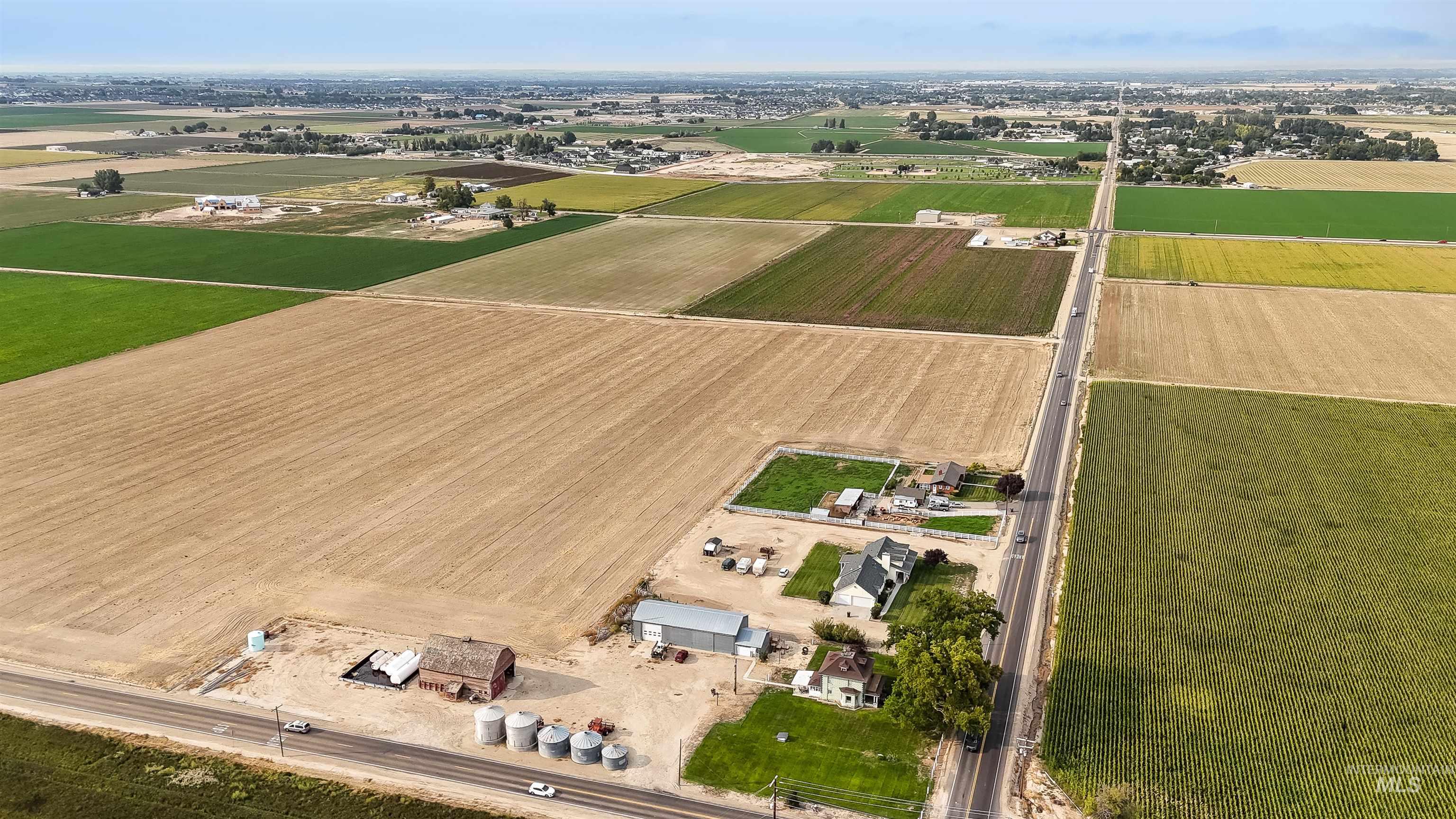 Aerial view of property and surrounding area featuring rural landscape and rows of crops