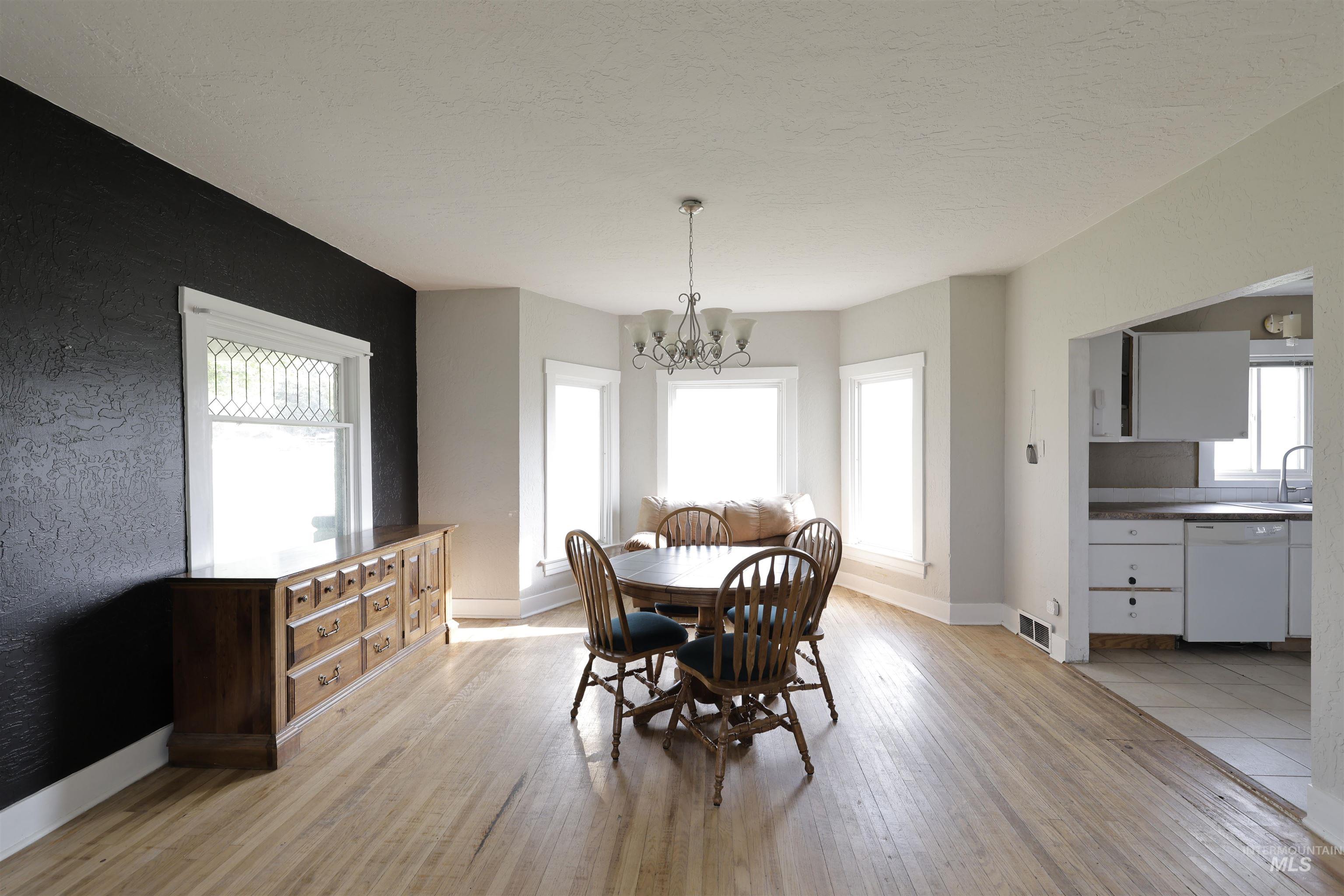 Dining space with light wood-type flooring, a chandelier, and a textured ceiling