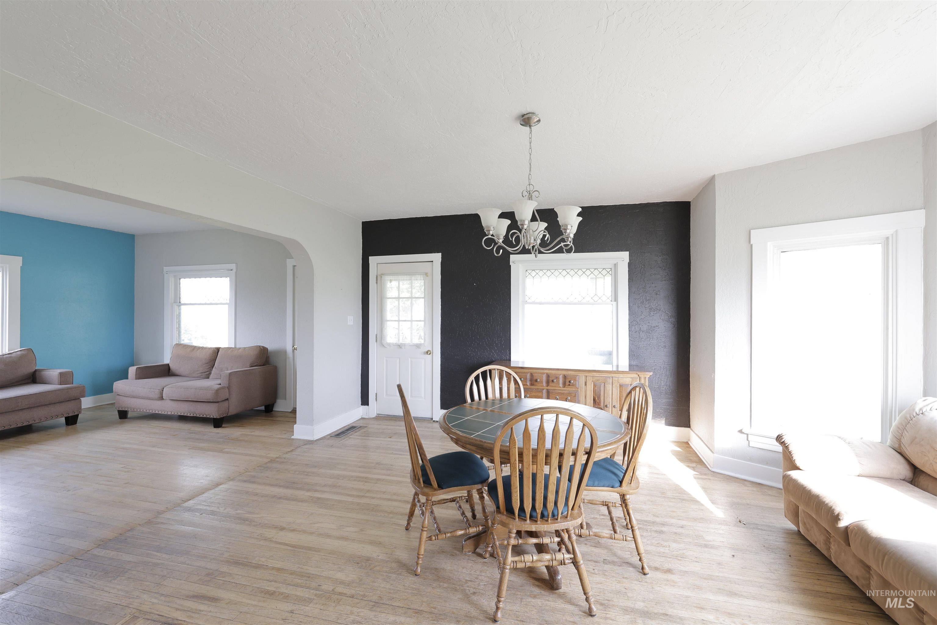 Dining area with arched walkways, wood finished floors, and a chandelier