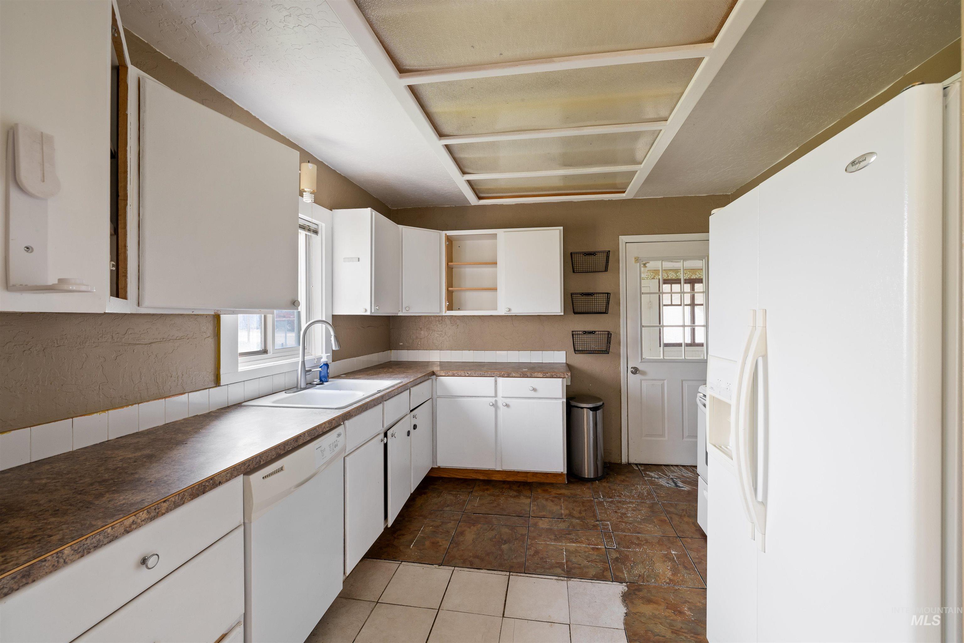 Kitchen with white appliances, white cabinetry, open shelves, and plenty of natural light