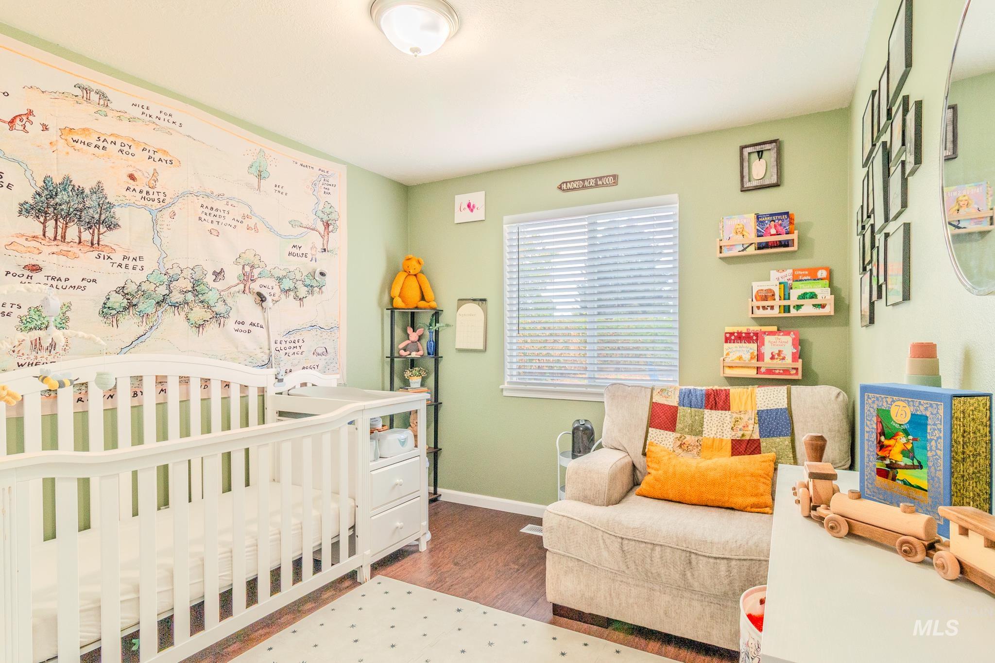 Bedroom with a nursery area and wood finished floors