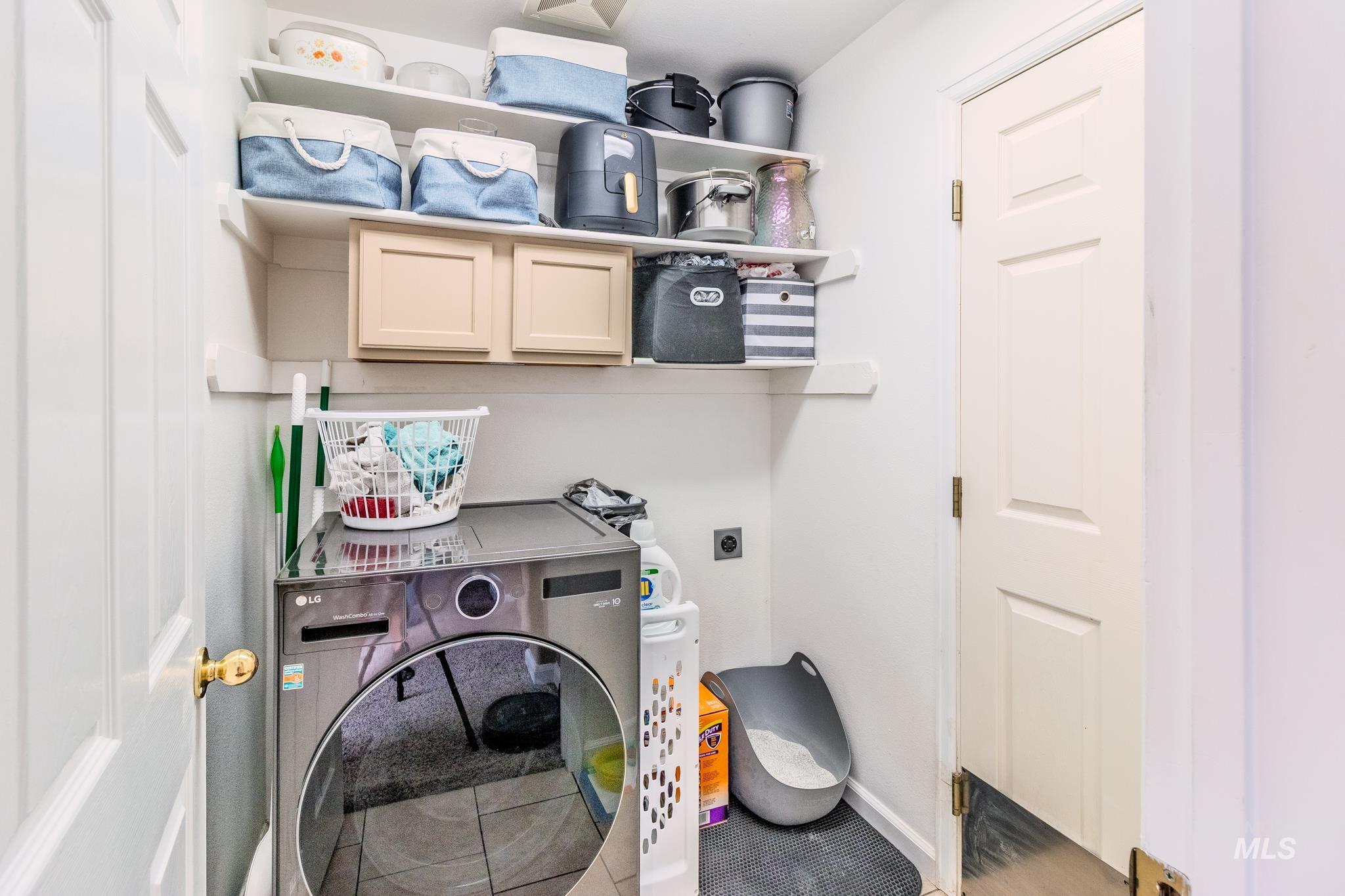 Laundry room featuring cabinet space and tile patterned flooring